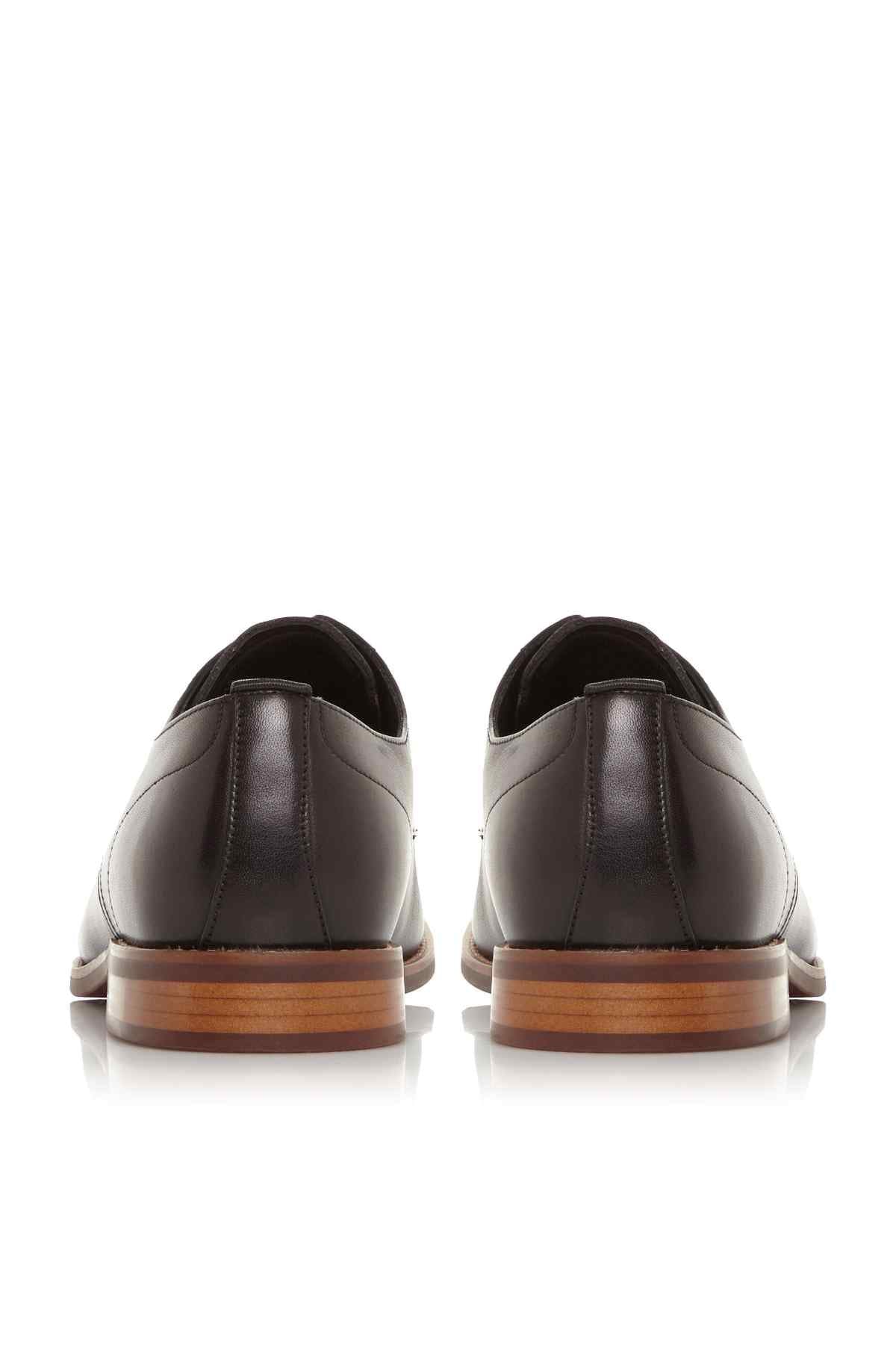 Black leather lace-up oxford shoes with heel seams and tan-trimmed soles