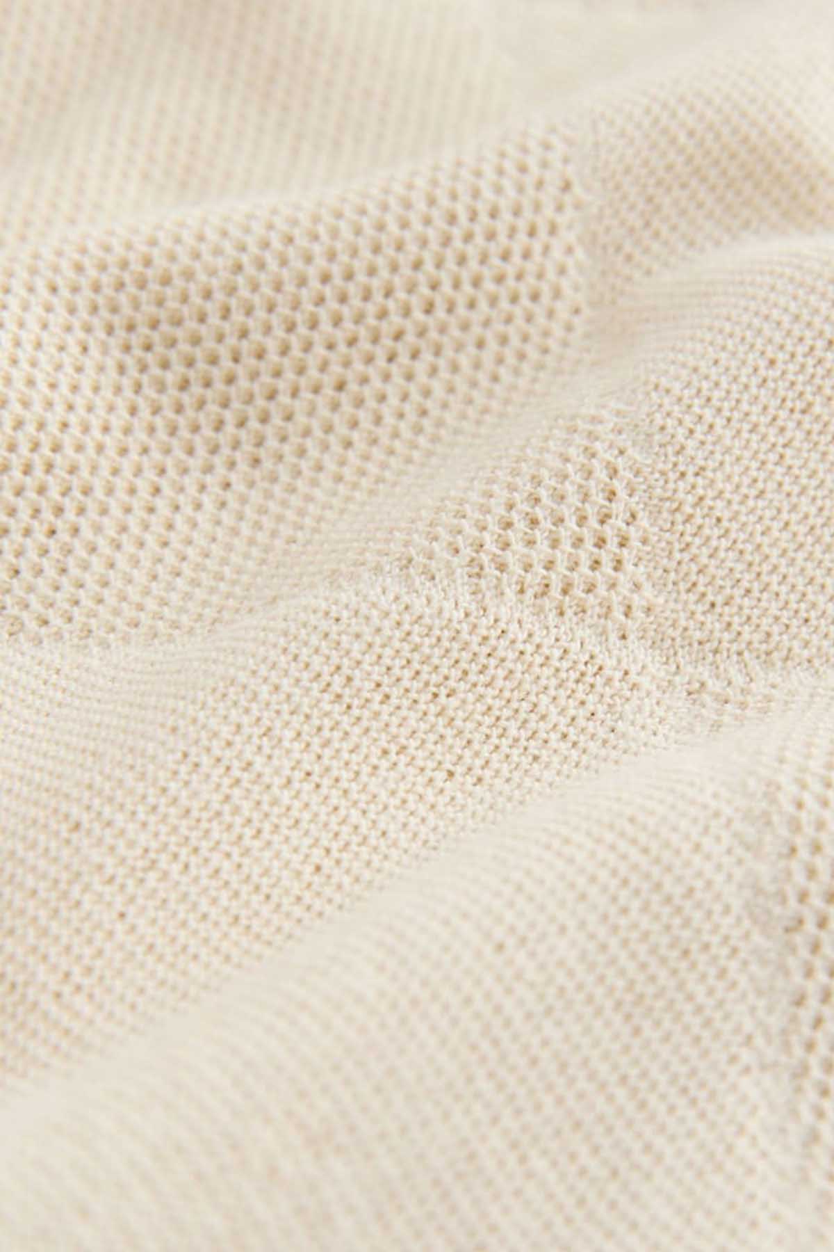 Cream woven fabric texture for NEXT polo shirt, close-up