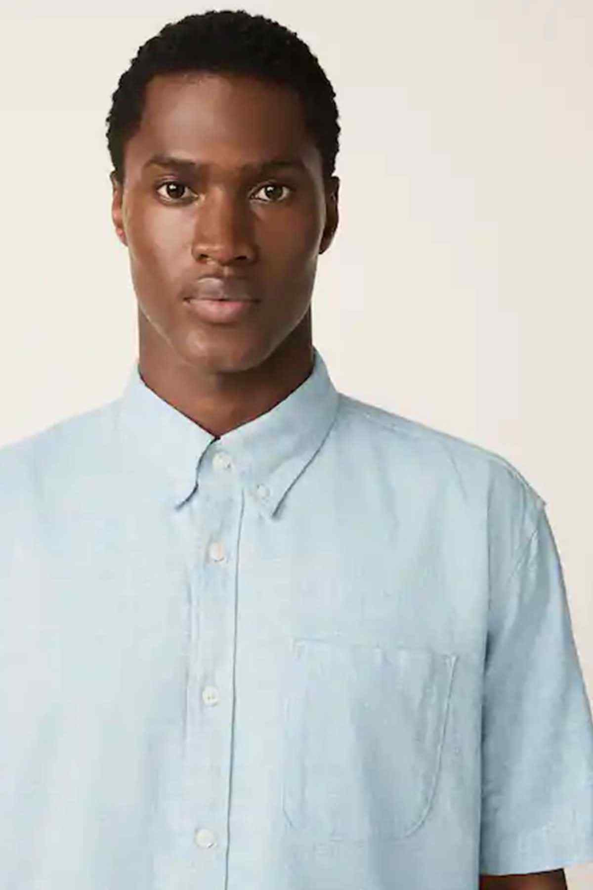 Light blue short-sleeve button-up shirt close-up of button placket and chest pocket.