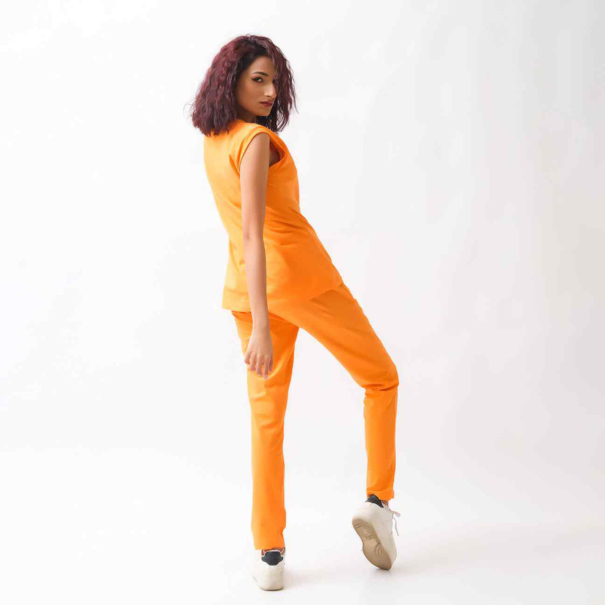 Orange sleeveless jumpsuit with crew neck and tapered pants, side view