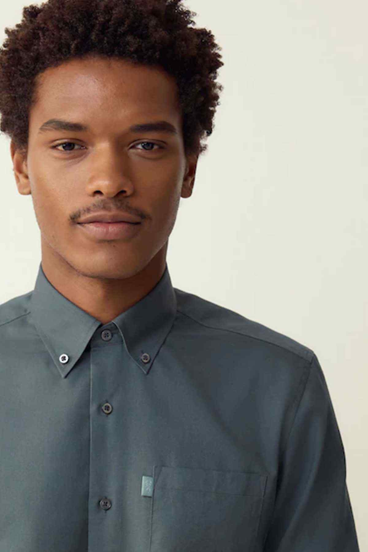 Men's petrol blue button-up shirt collar and front buttons with chest patch