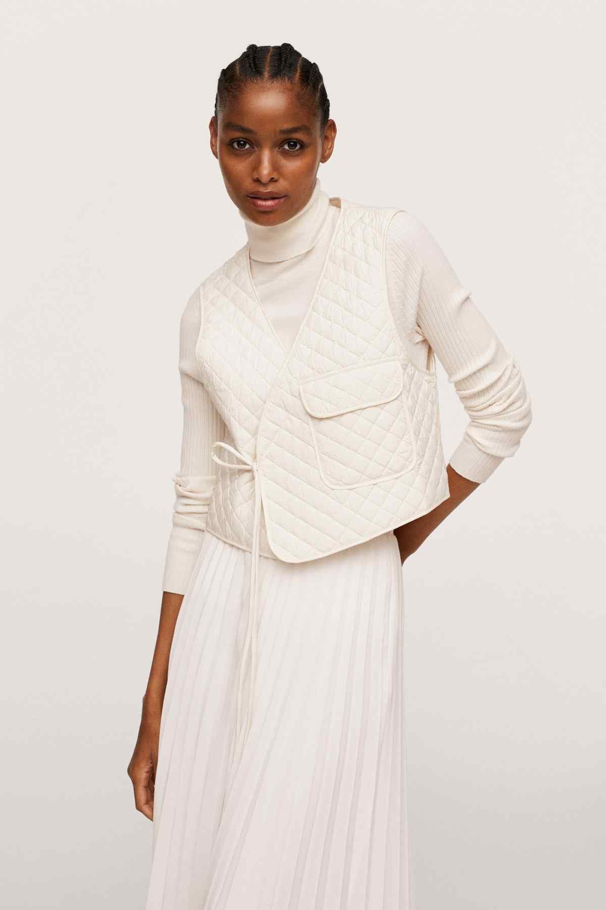 Ecru quilted long-sleeve jacket with side drawcord tie over pleated skirt