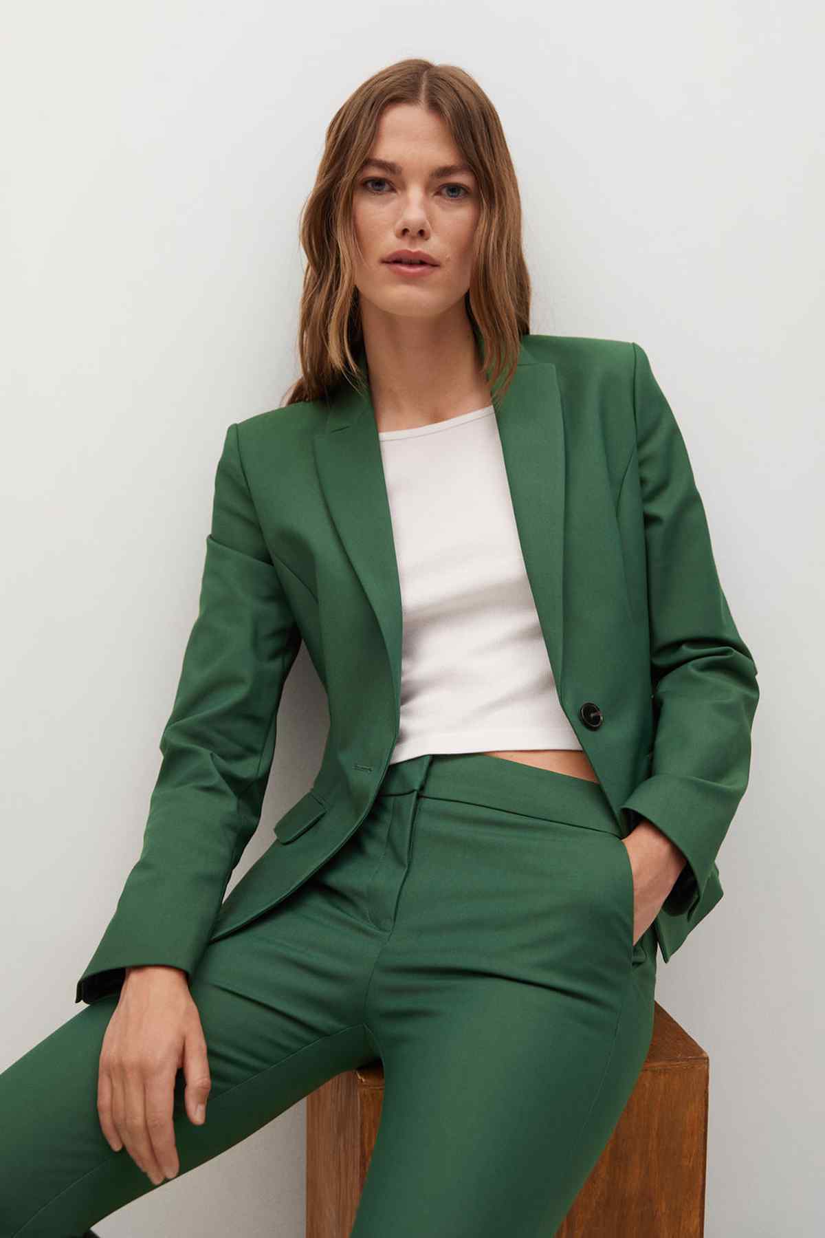 Dark green tailored blazer over white top with slim trousers