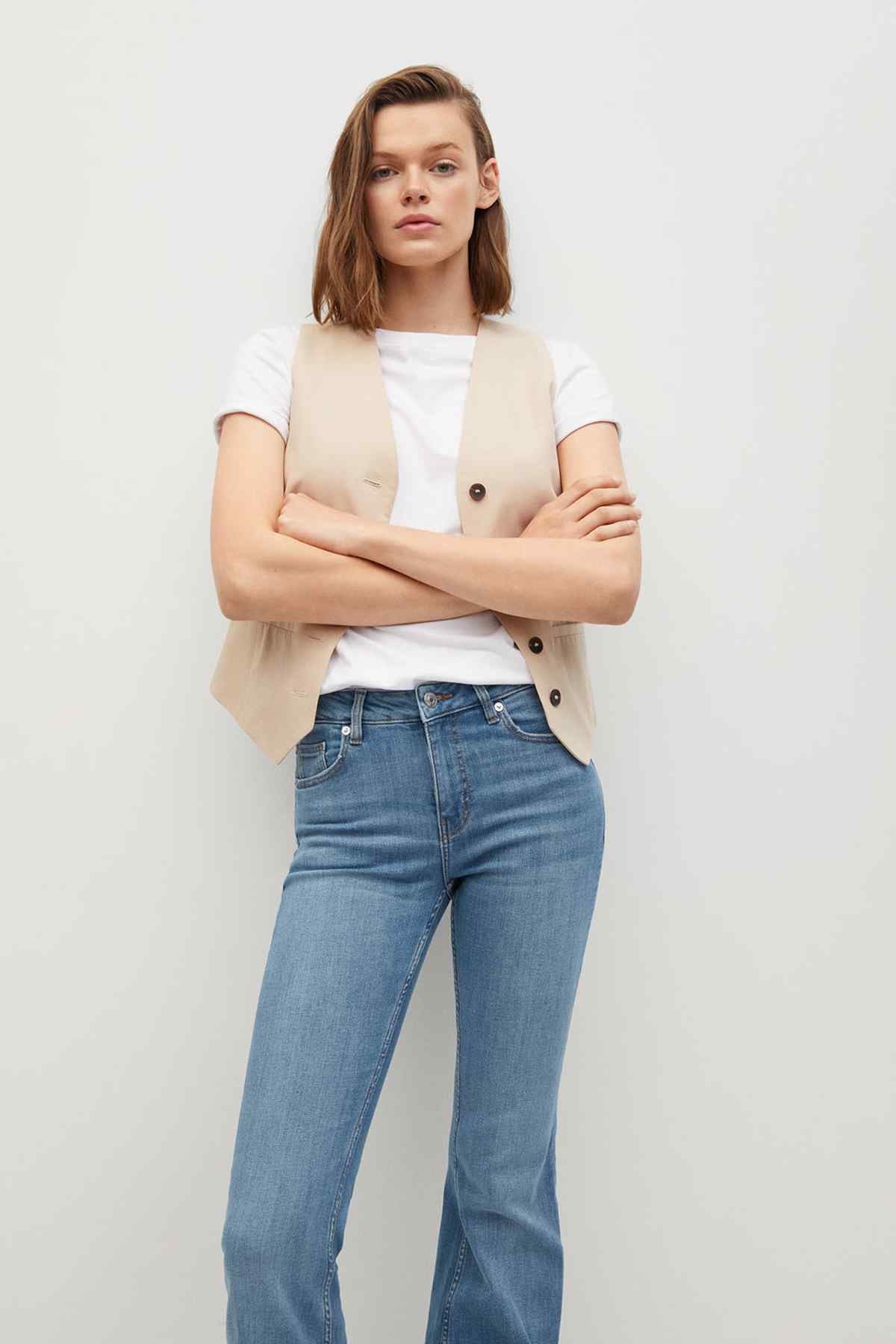 Beige sleeveless button vest over white T-shirt with medium-blue straight jeans
