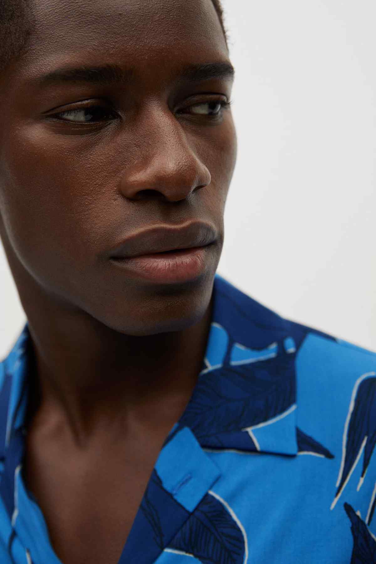 Blue leaf-print short-sleeve button-up shirt close-up with point collar