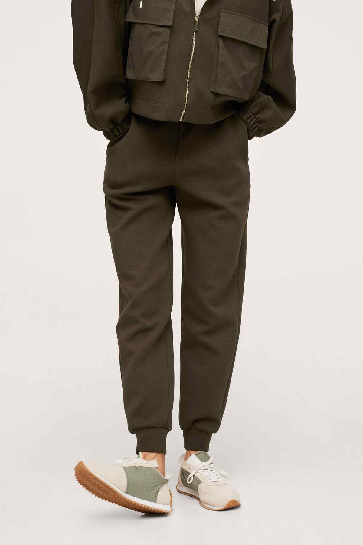Olive jogger pants with elastic cuffs, worn with light sneakers