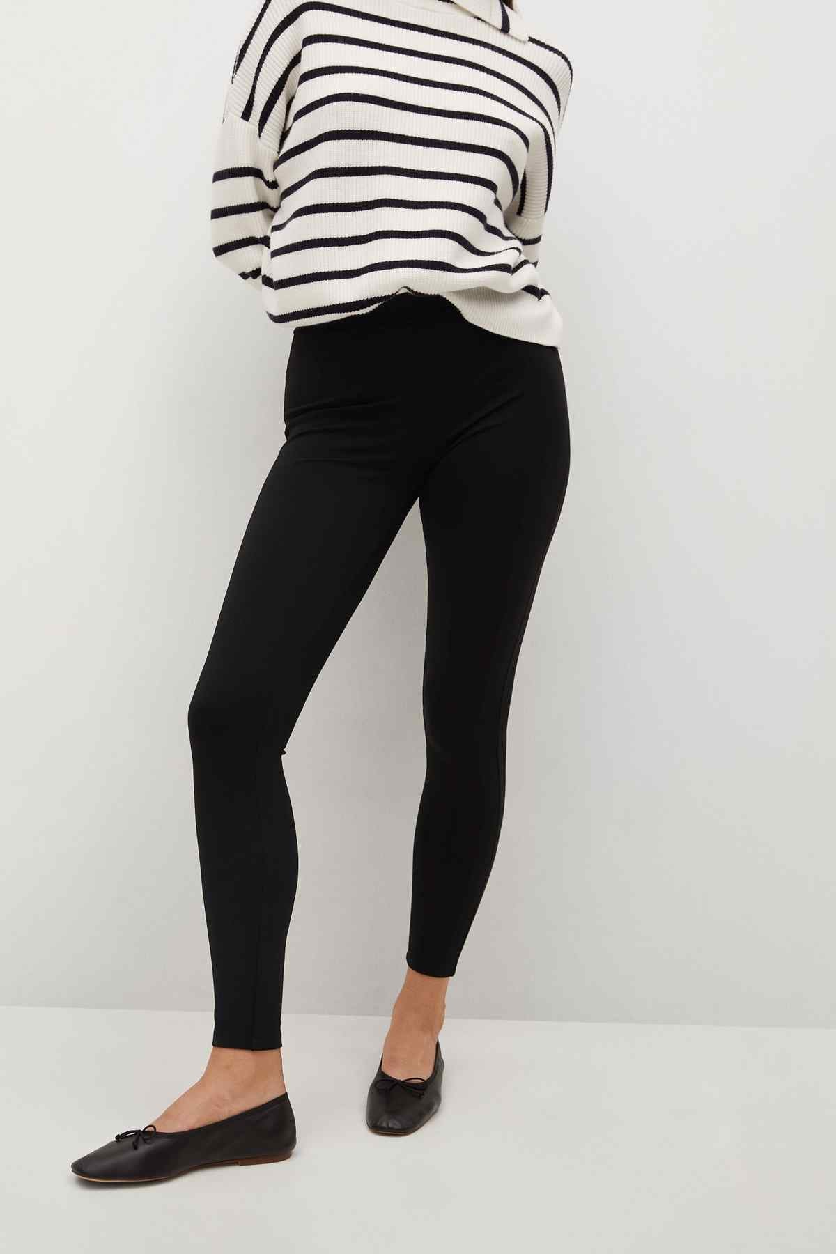 Black ankle-length leggings, close-up of slim legs and cuffs