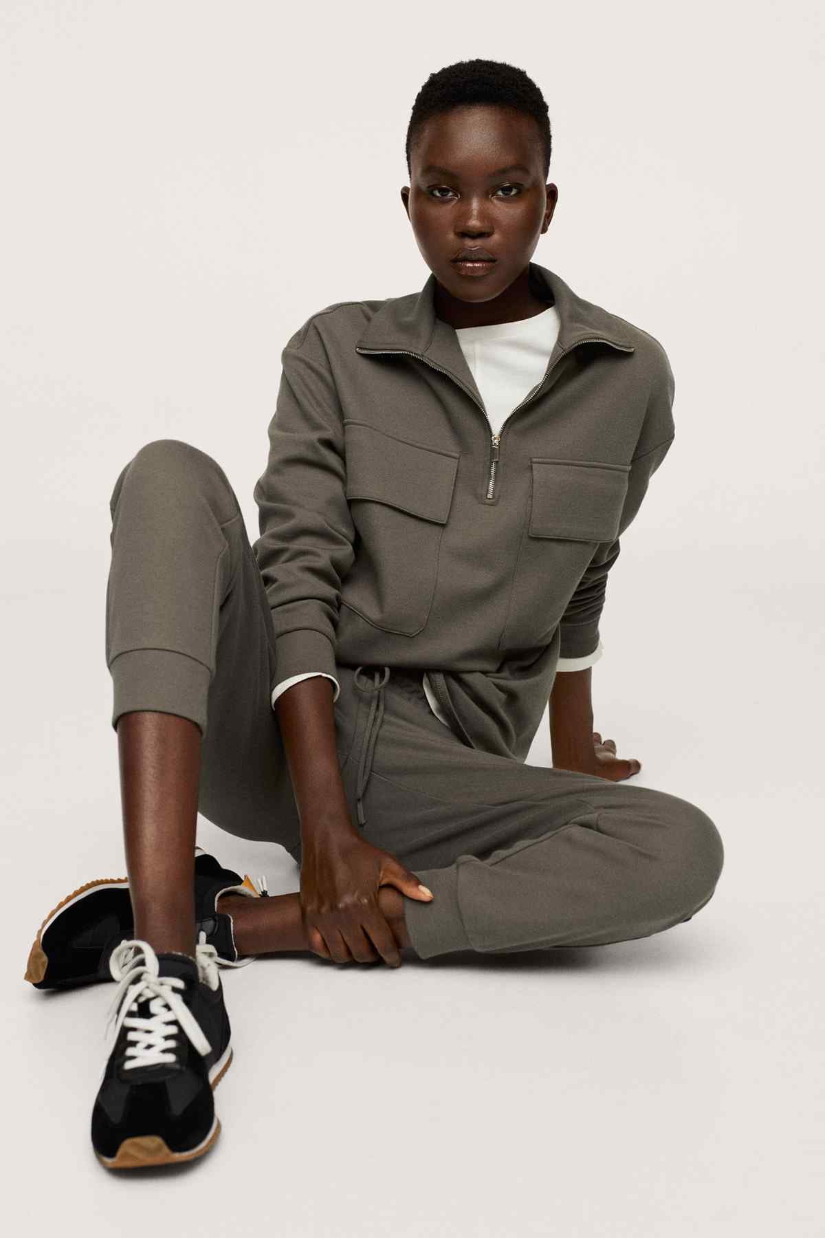 Khaki zip-collar tracksuit with side pockets and elastic cuffs, seated view