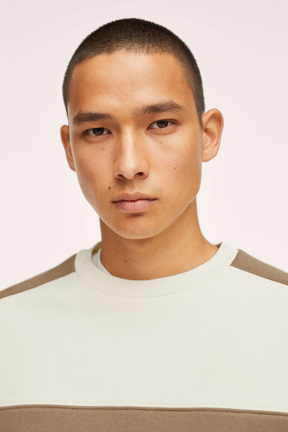 Ecru crewneck sweatshirt close-up with tan horizontal stripe at chest