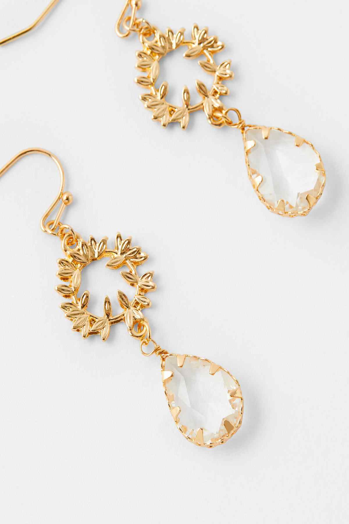Gold crystal drop earrings close-up with floral cluster and teardrop crystal dangle