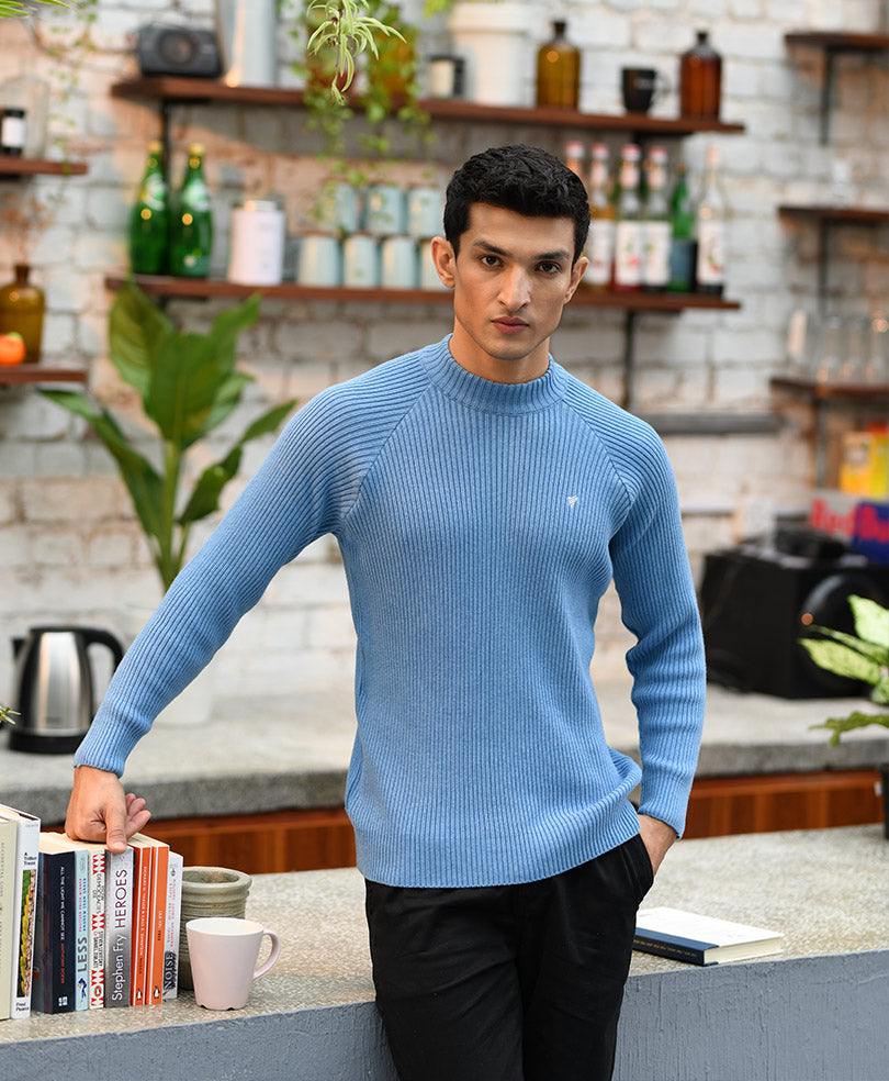 Fitted blue knit sweater with ribbed crew neck, holding stack of books