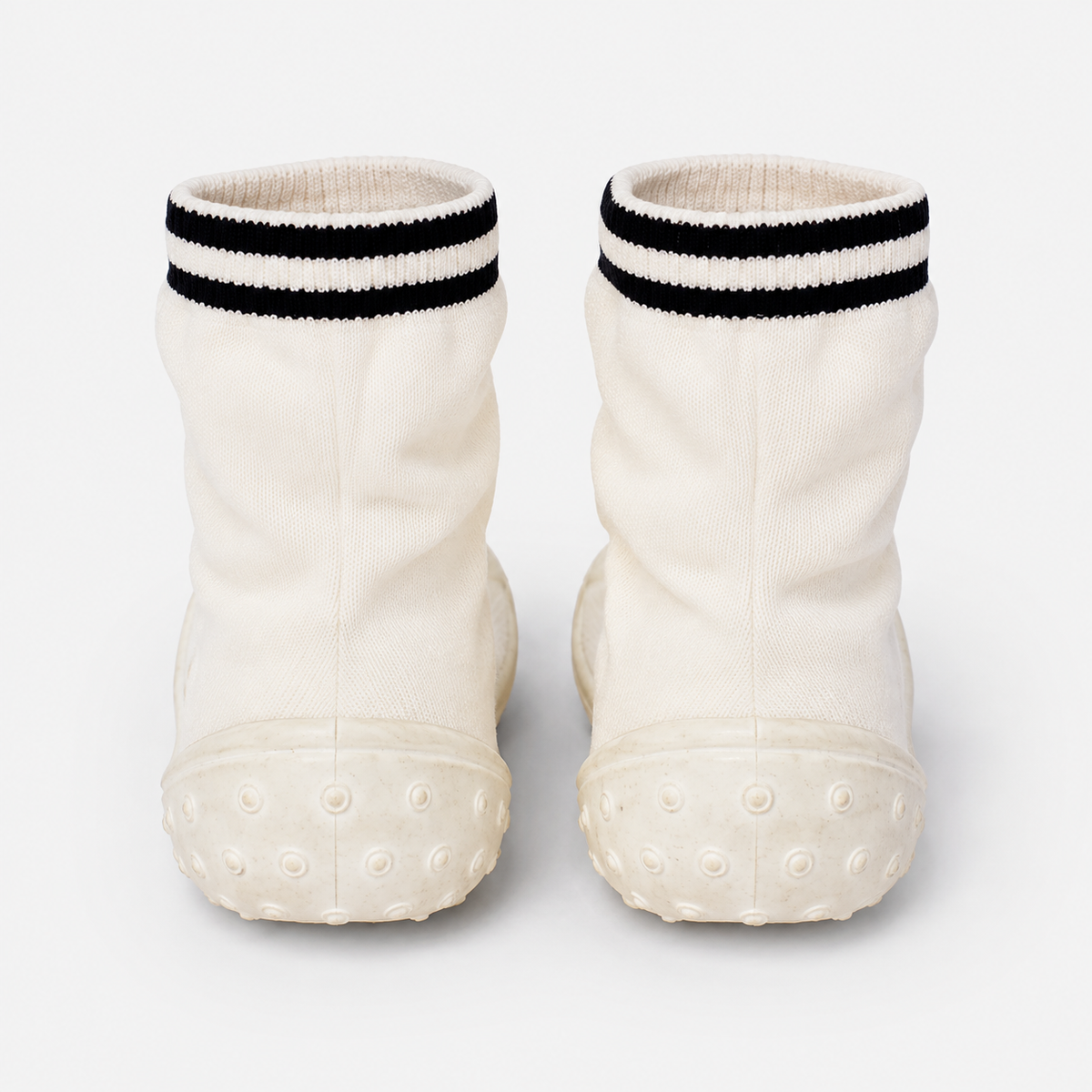 White knit baby socks with black striped cuffs and textured rubber sole dots