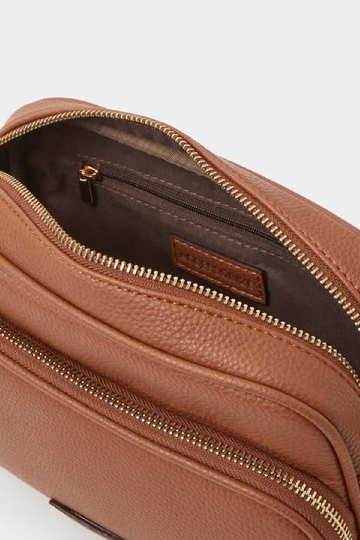 Tan leather-look crossbody bag close-up with dual zippers and logo patch