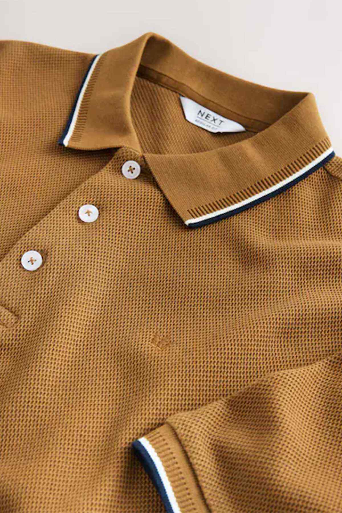 Tan polo shirt collar and button placket close-up with white-and-navy trim