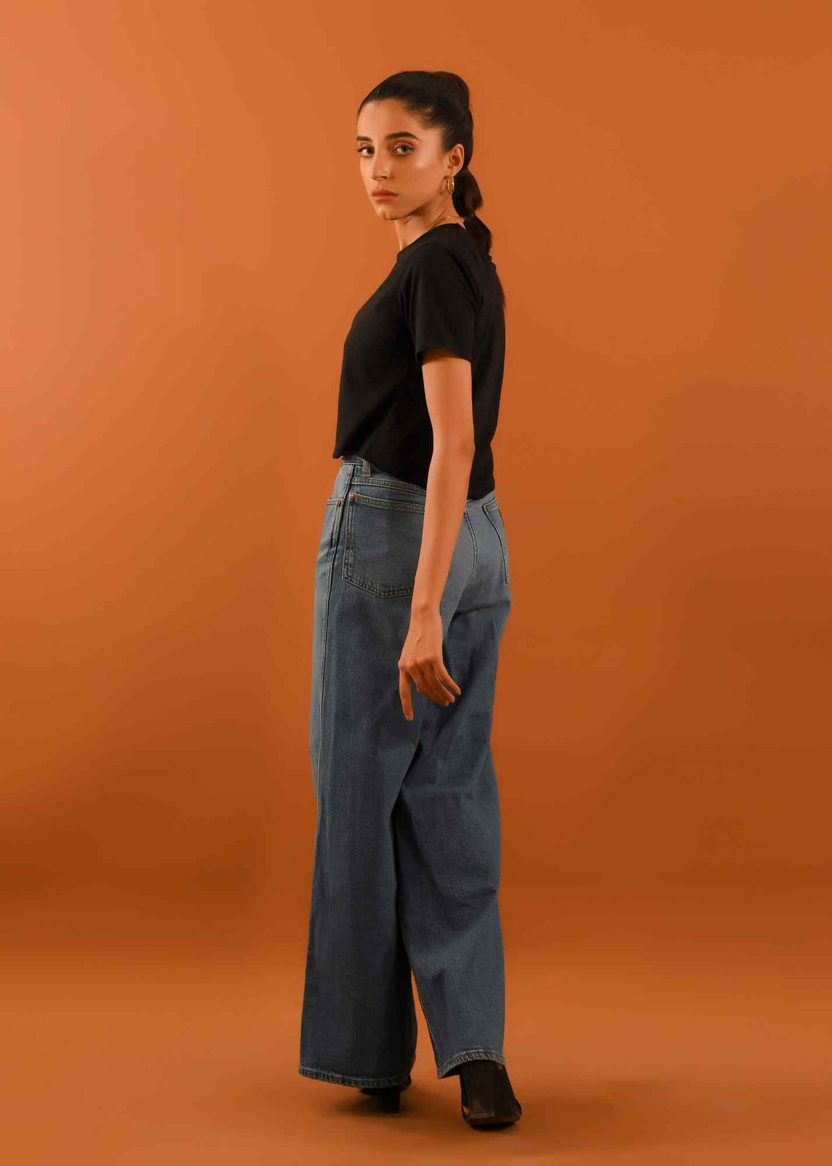 Black cropped T-shirt with short sleeves and light-wash wide-leg jeans, side view