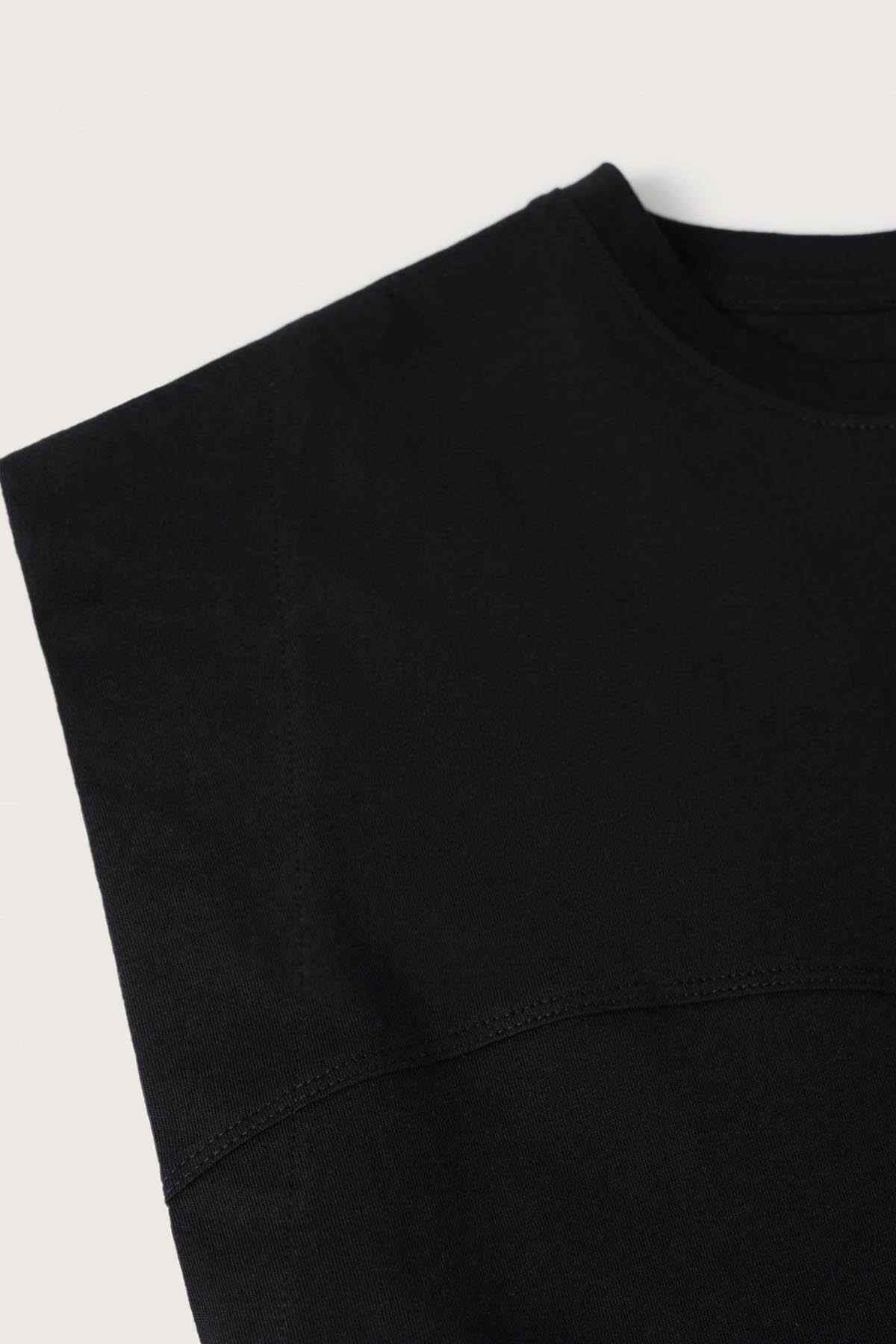 Black sleeveless top fabric close-up with stitched crew-neck edge