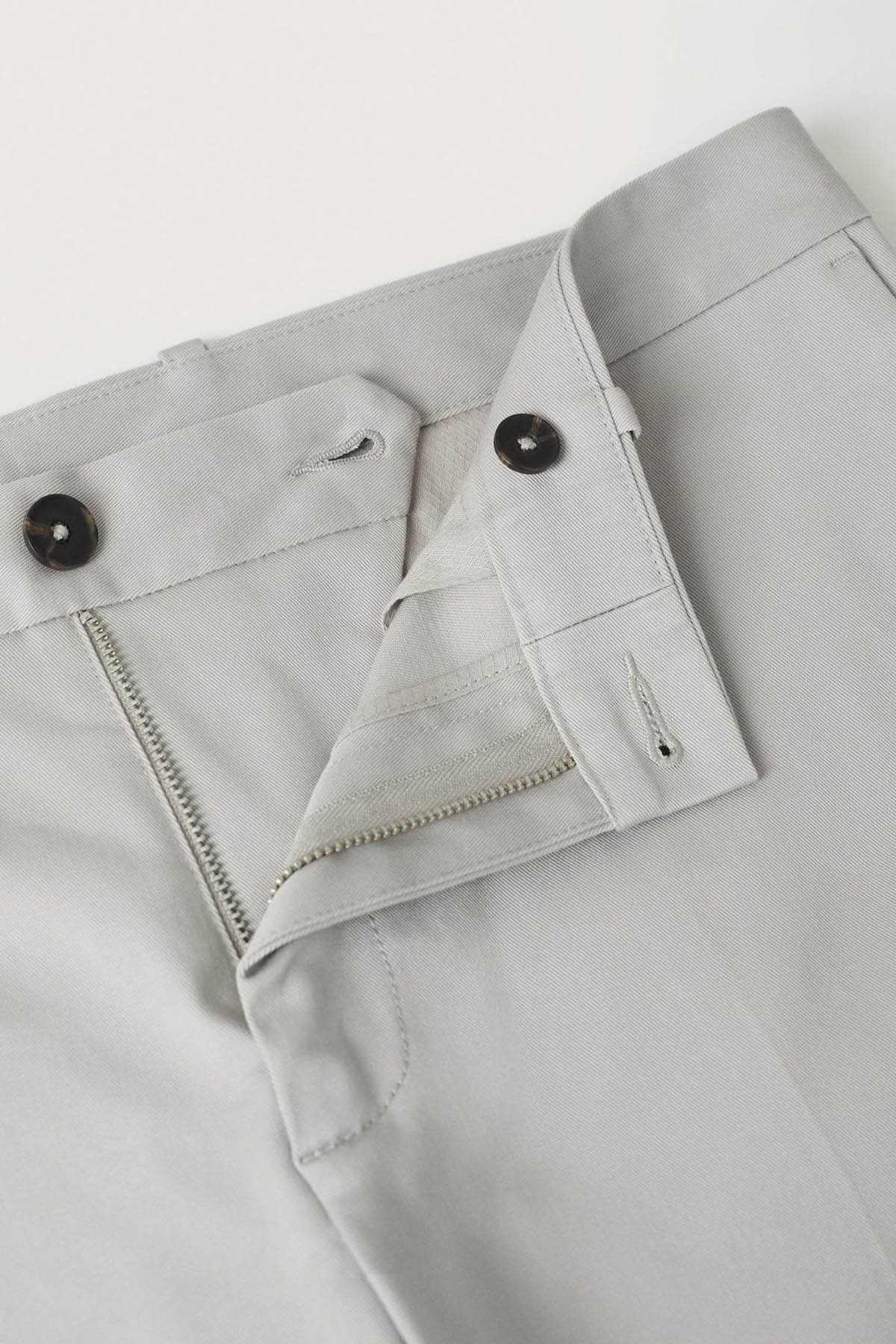 Grey button-fly trouser front with belt loops and zip pocket detail