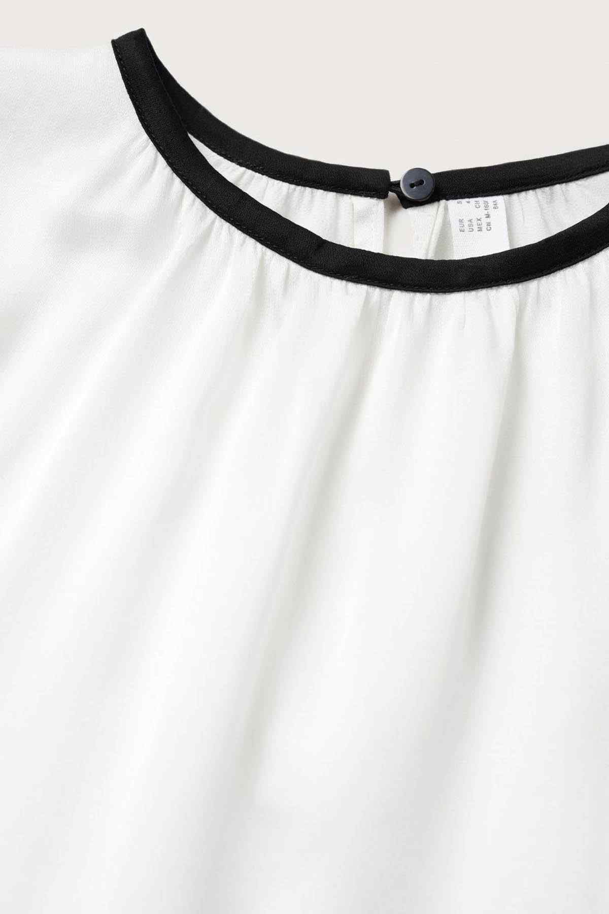 Ecru sleeveless blouse neckline with black band and small button
