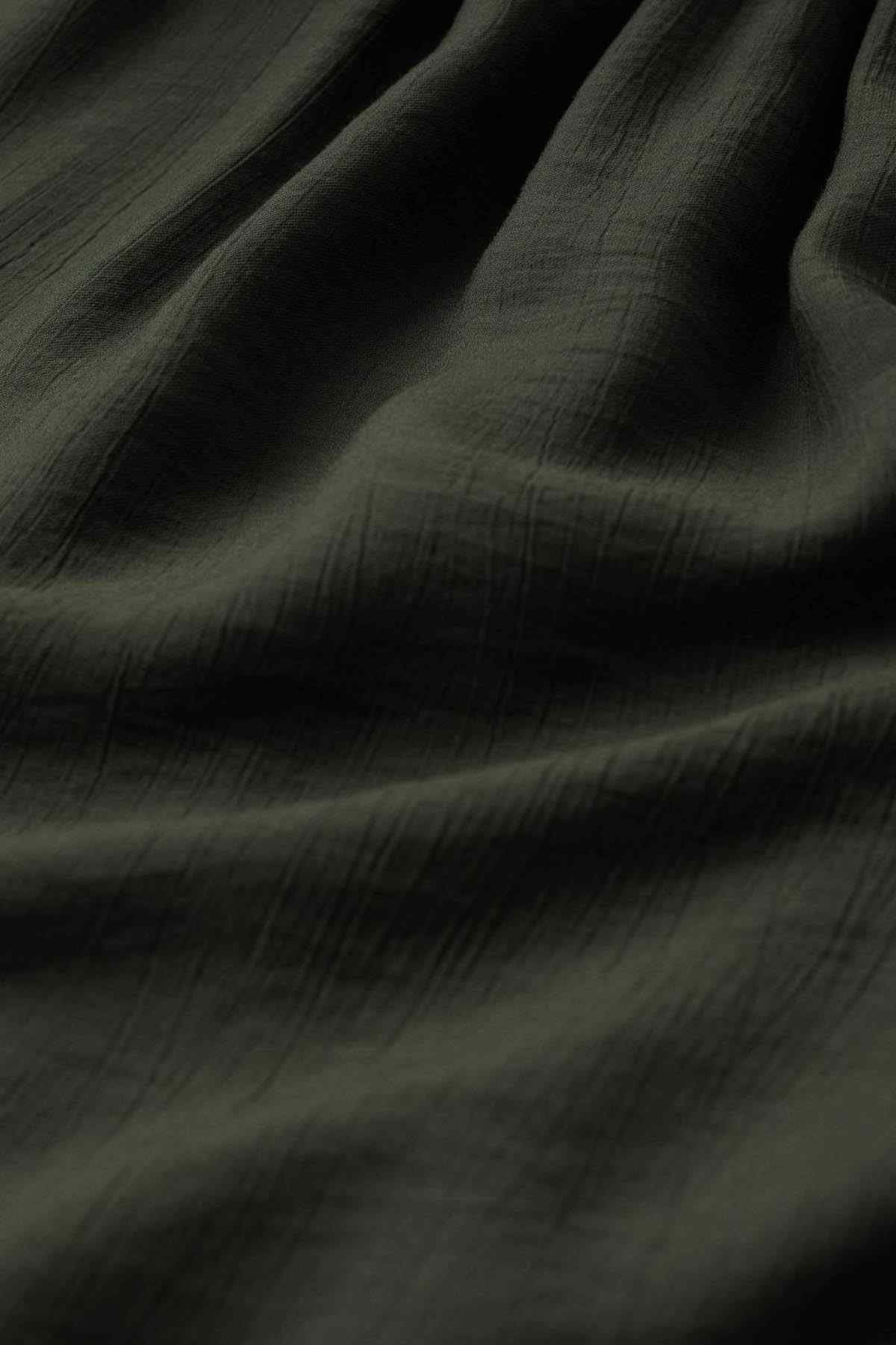 Dark green textured fabric with soft drape and subtle woven pattern