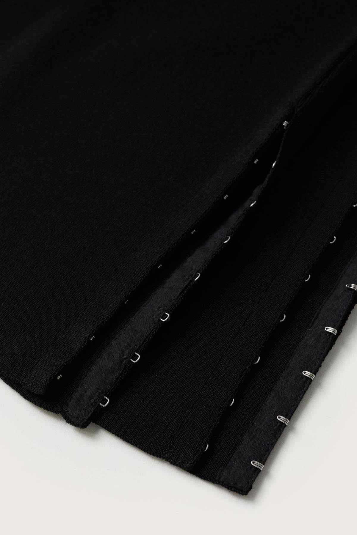 Black trouser hem with decorative button accents along the cuff