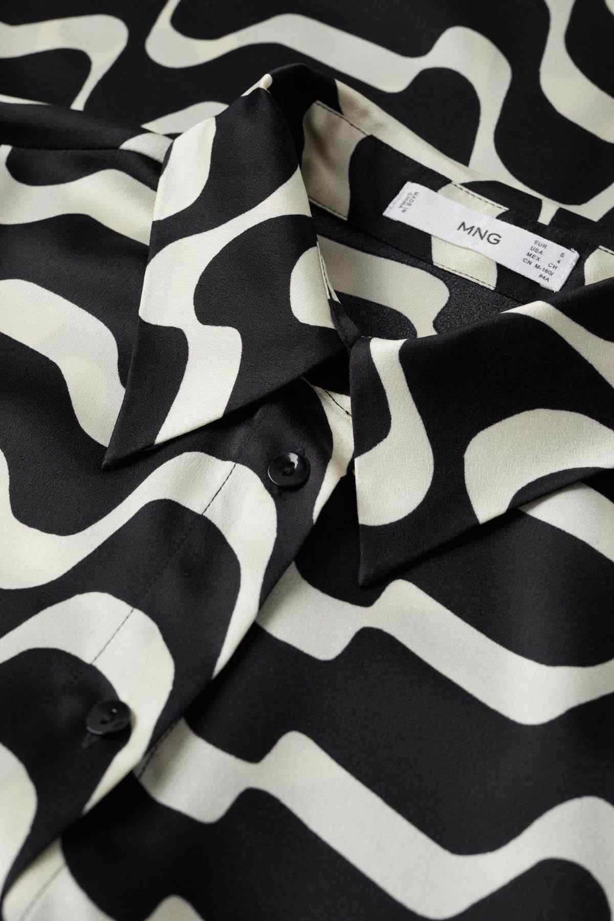 Black and white wave-pattern shirt fabric closeup with button and size label