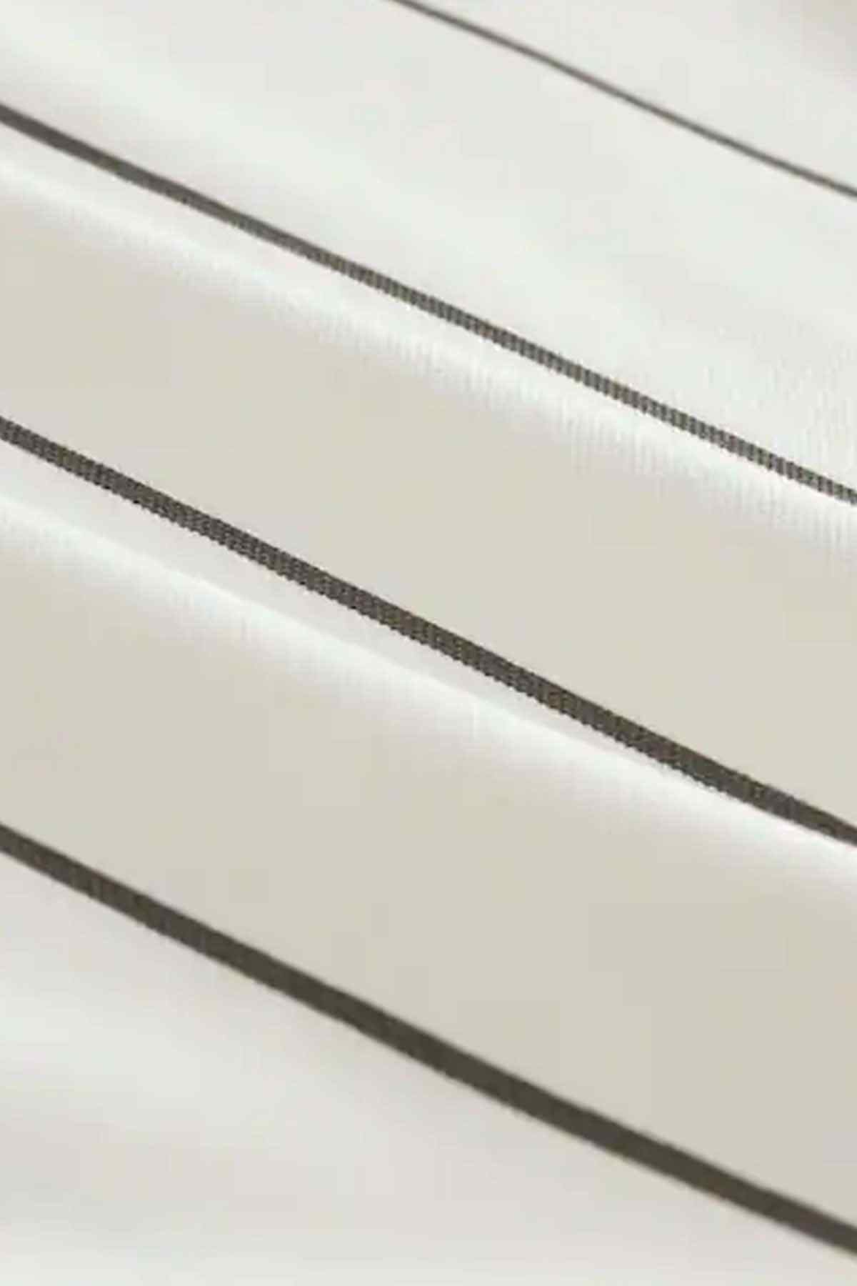 Close-up of kids white T-shirt fabric with dark vertical stripe stitching