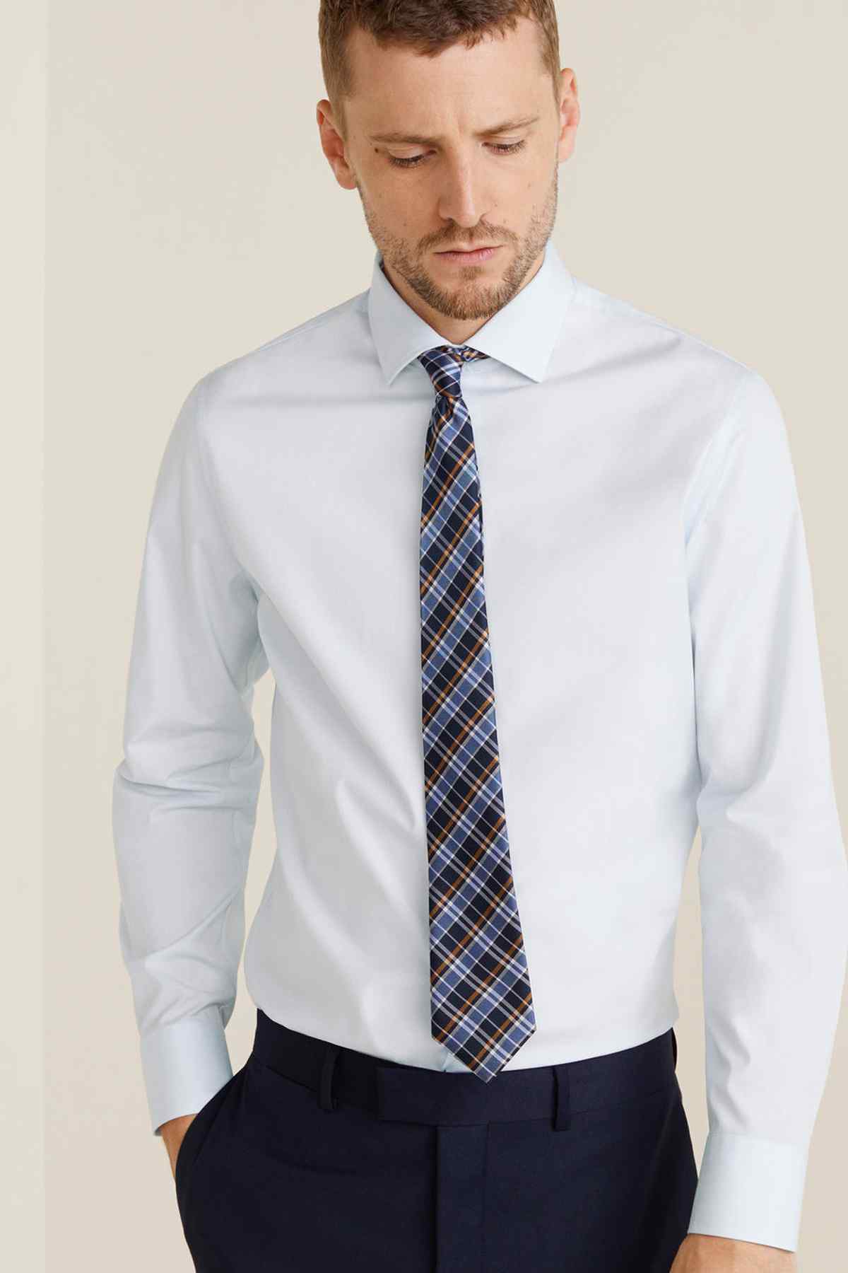 Men's light blue dress shirt with plaid necktie and pointed collar