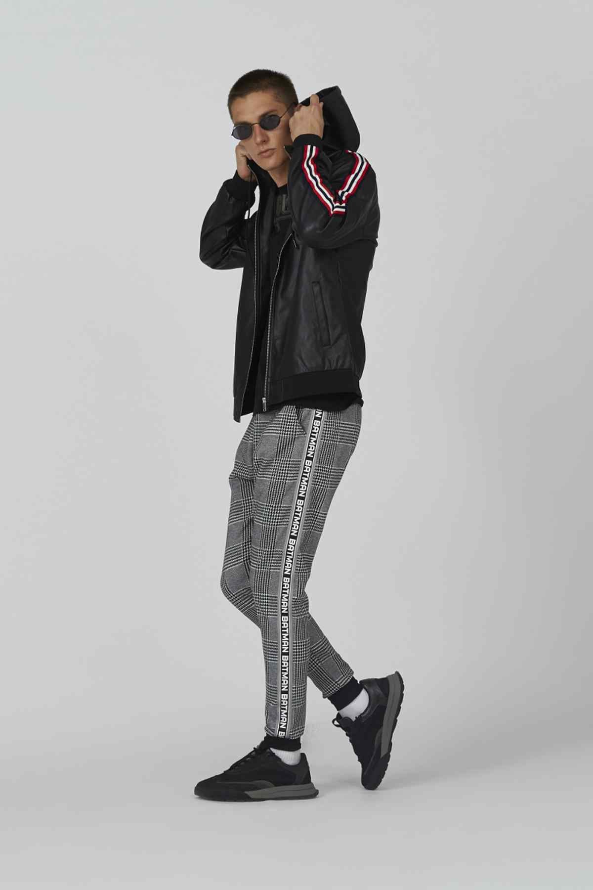 Black hooded zip jacket with striped trim; plaid pants visible