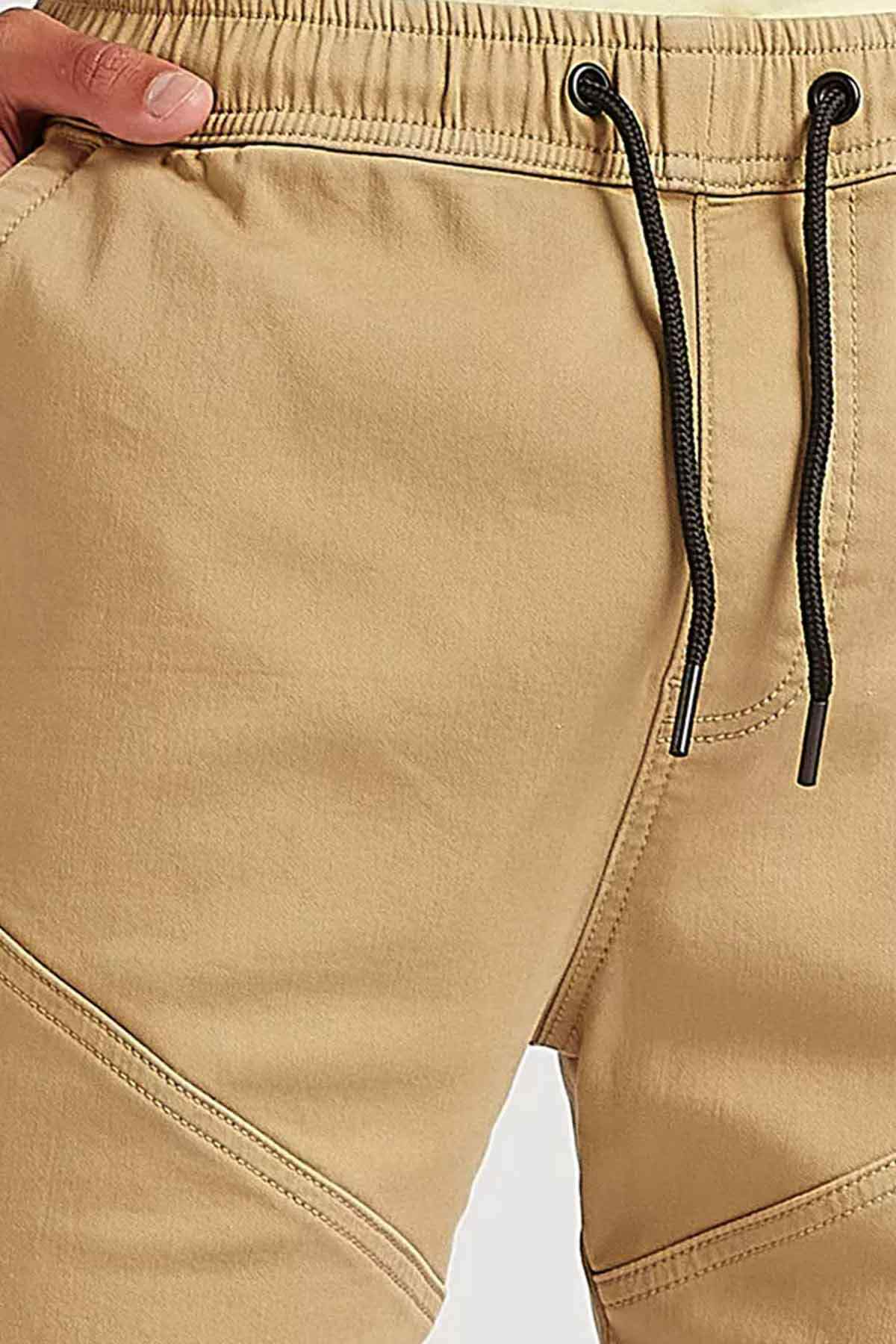 Beige shorts close-up: elastic waistband with black drawstring and seam stitching