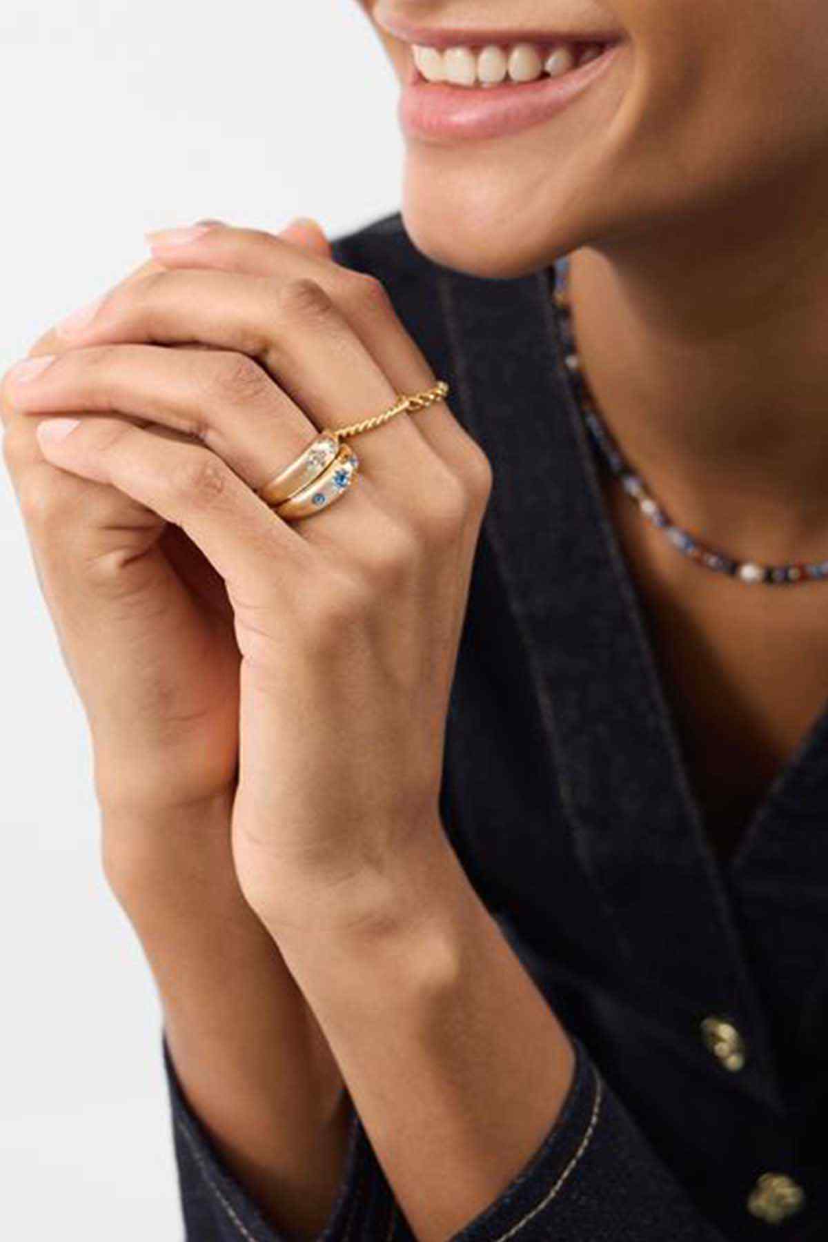 Gold-tone rings with blue stones worn on hand
