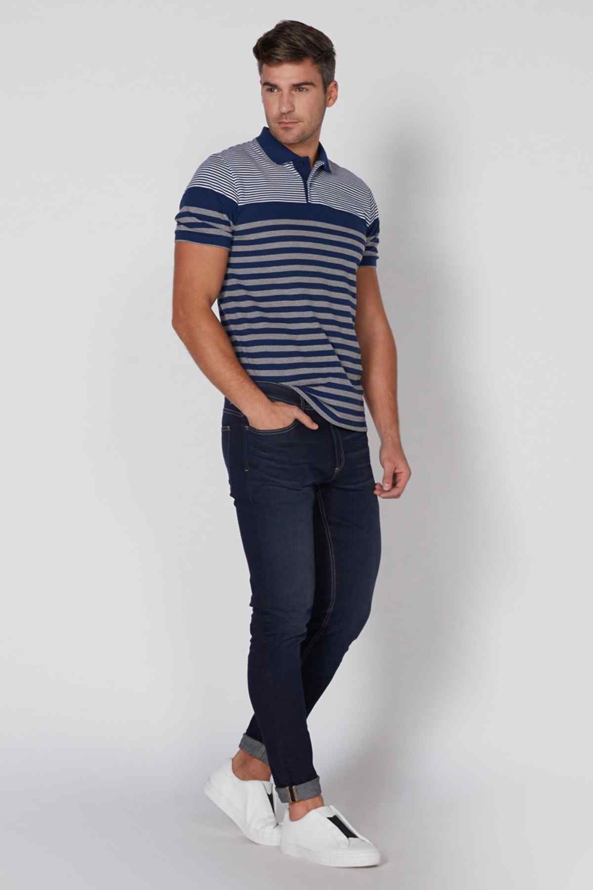 Men's blue striped polo shirt, walking view with dark jeans and white sneakers