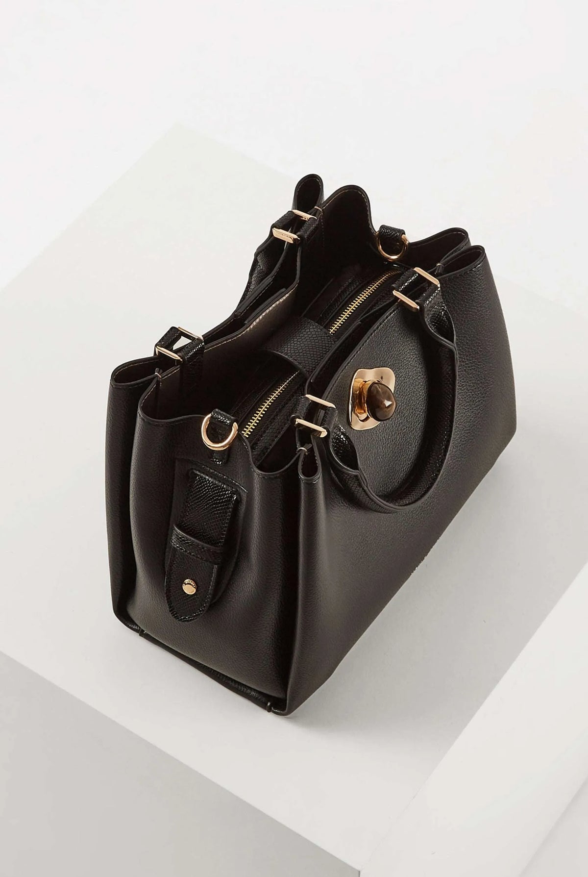 Black structured handbag with side buckles, gold hardware, and front pockets