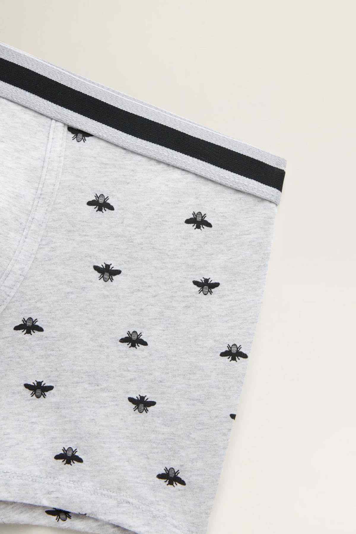 Grey boxer briefs fabric close-up with dark waistband and black spider print