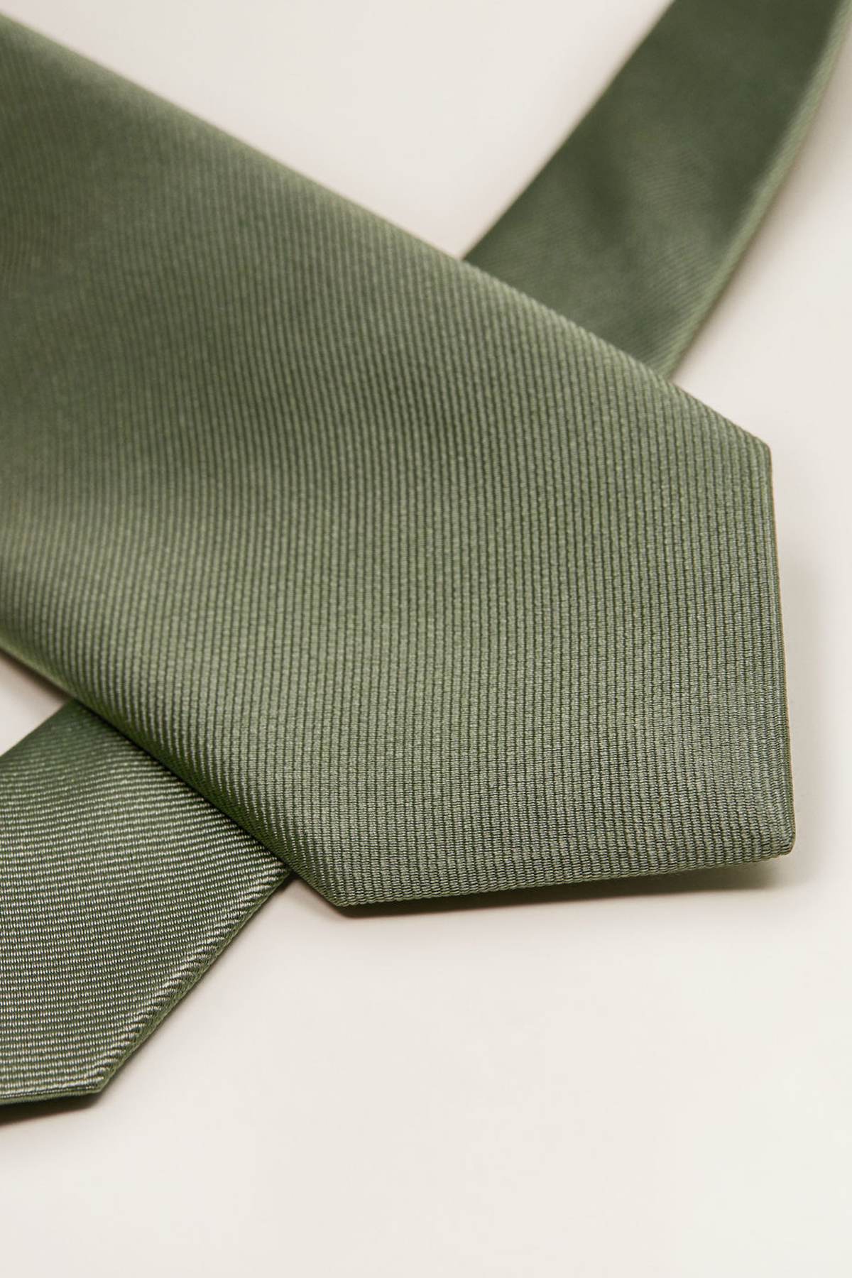 Khaki textured necktie, close-up of pointed tip and diagonal weave