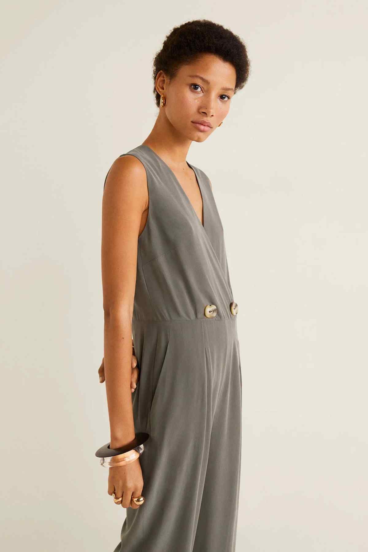 Gray sleeveless V-neck jumpsuit with button waist detail and draped front.