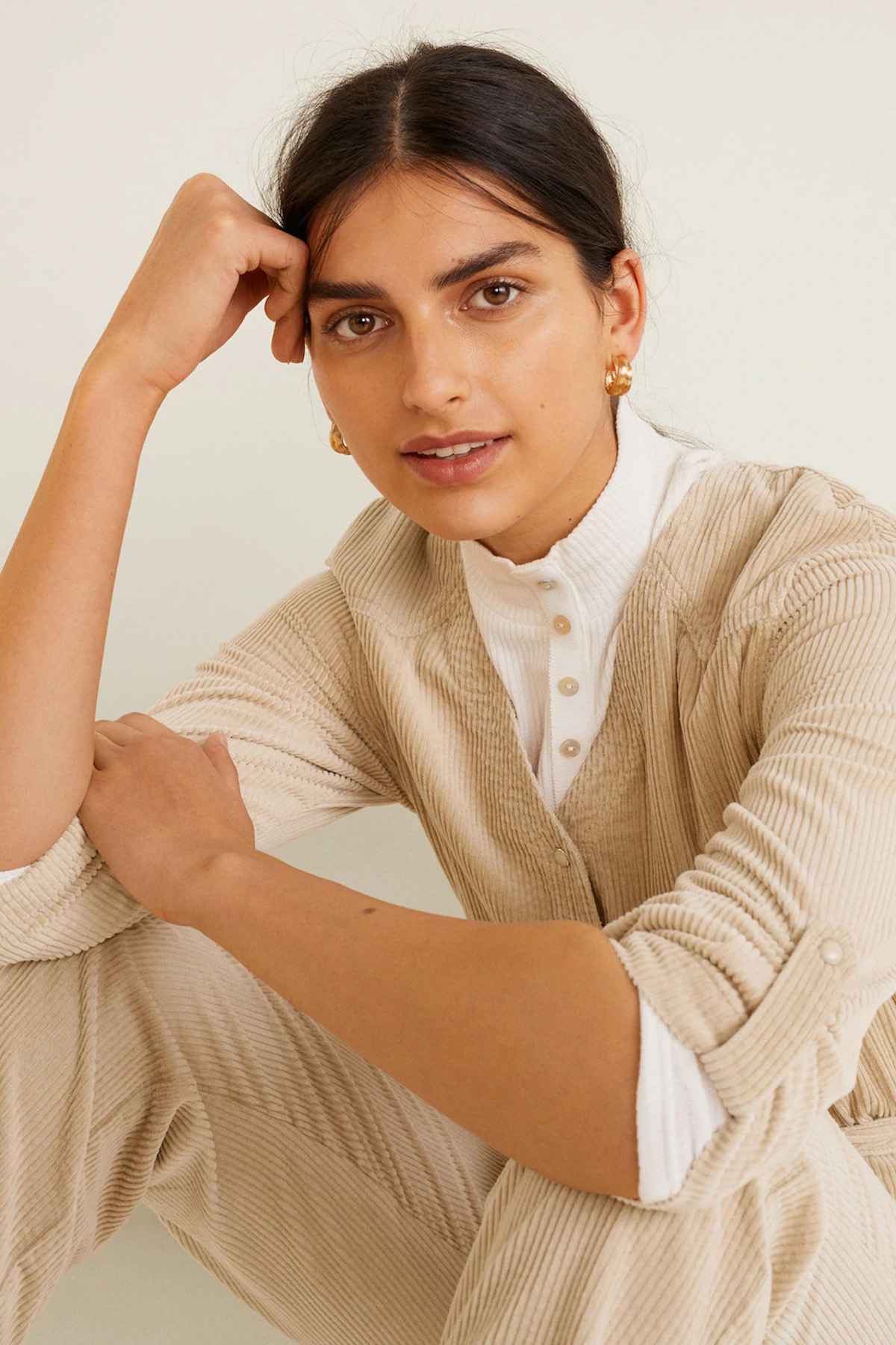 Beige belted jumpsuit close-up with textured knit and button details