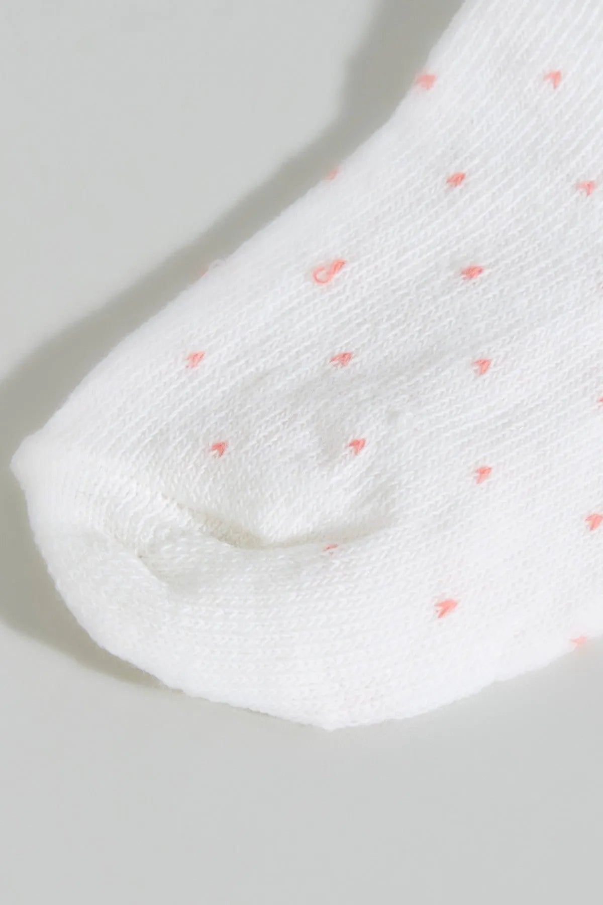 Cream knit ankle sock with small coral dot pattern and orange cuff trim