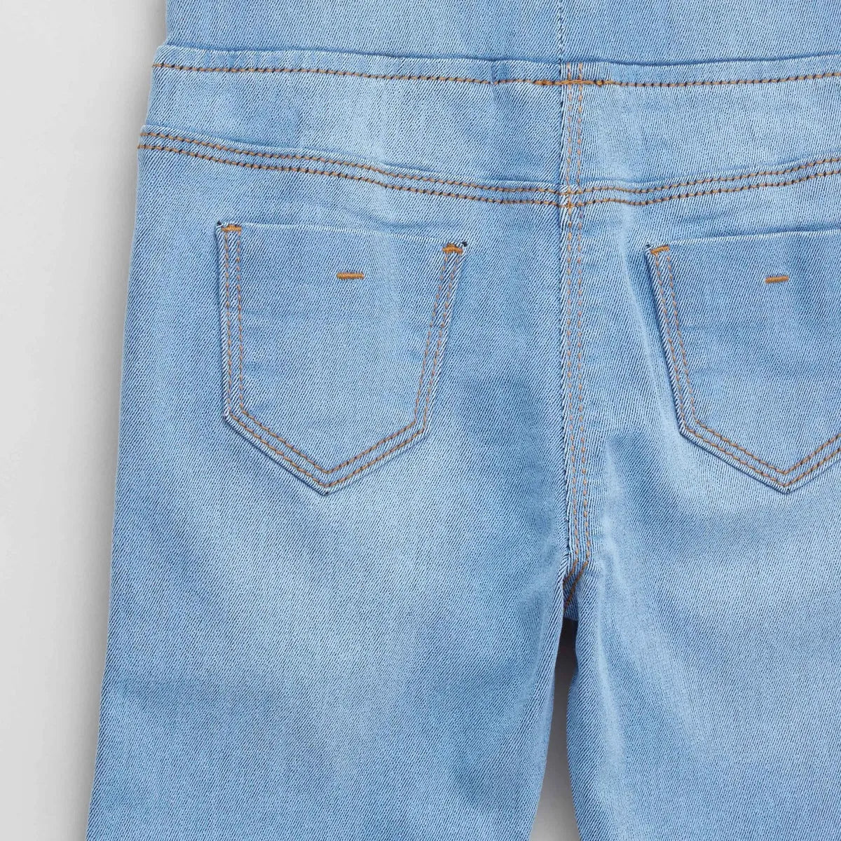 Light blue denim baby pants front pocket close-up with orange topstitching