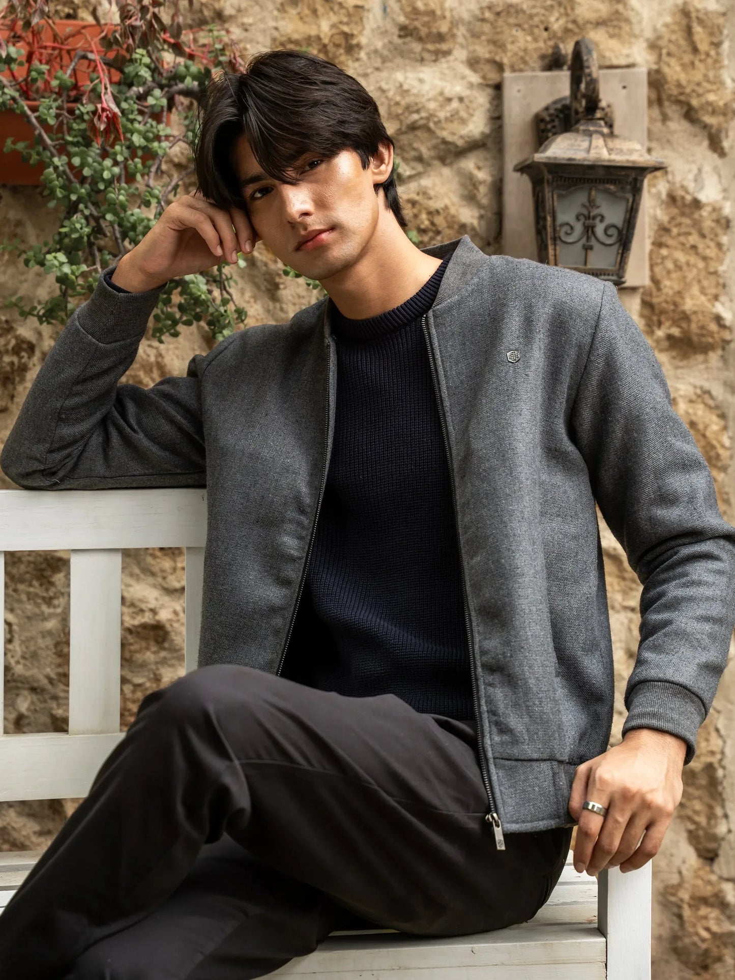 Grey zip-front jacket with mock collar, chest logo, and side pockets
