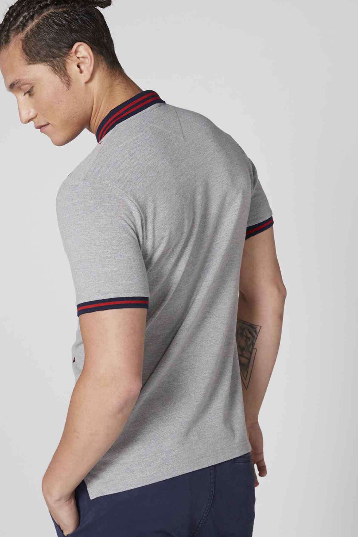 Men's grey polo shirt side view with red collar stripe and navy cuff trim