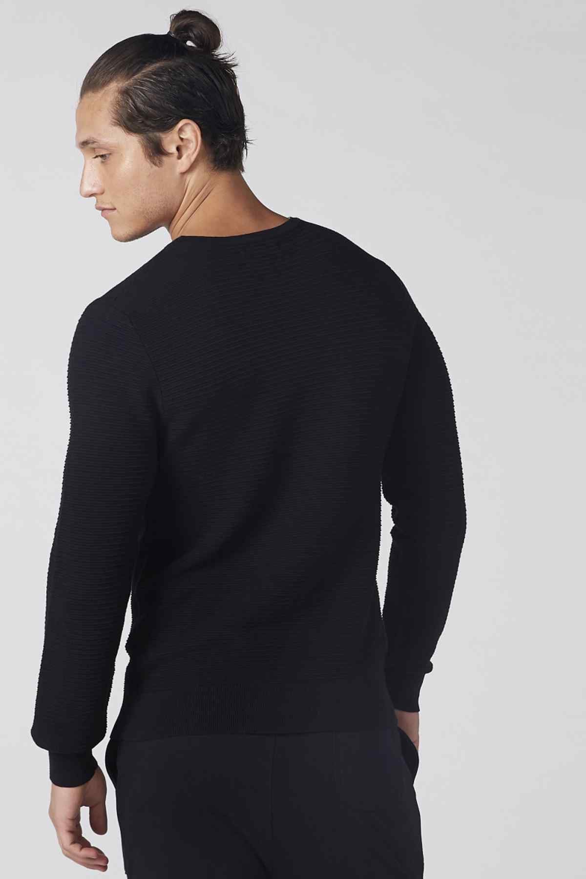 Black long-sleeve knit top from back view with ribbed cuffs