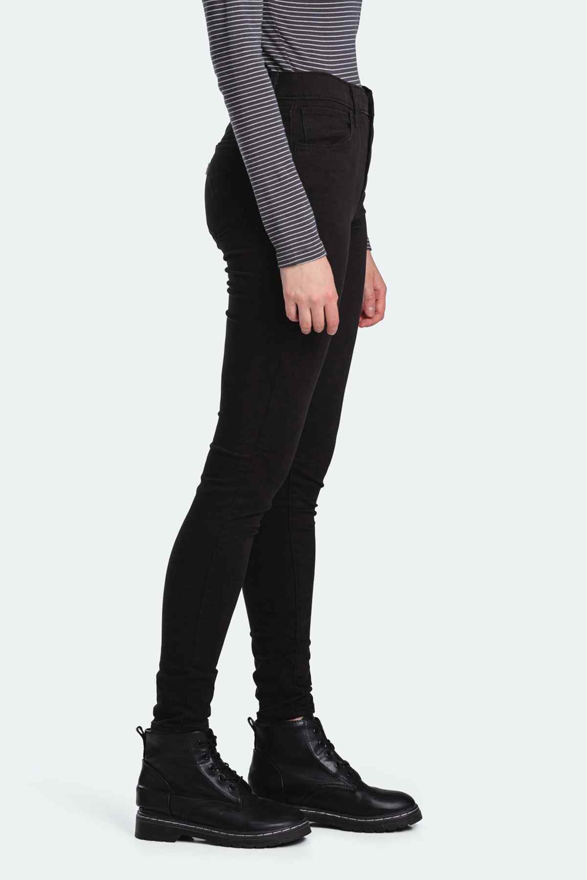 Black skinny jeans side view with zip fly and fitted leg opening.