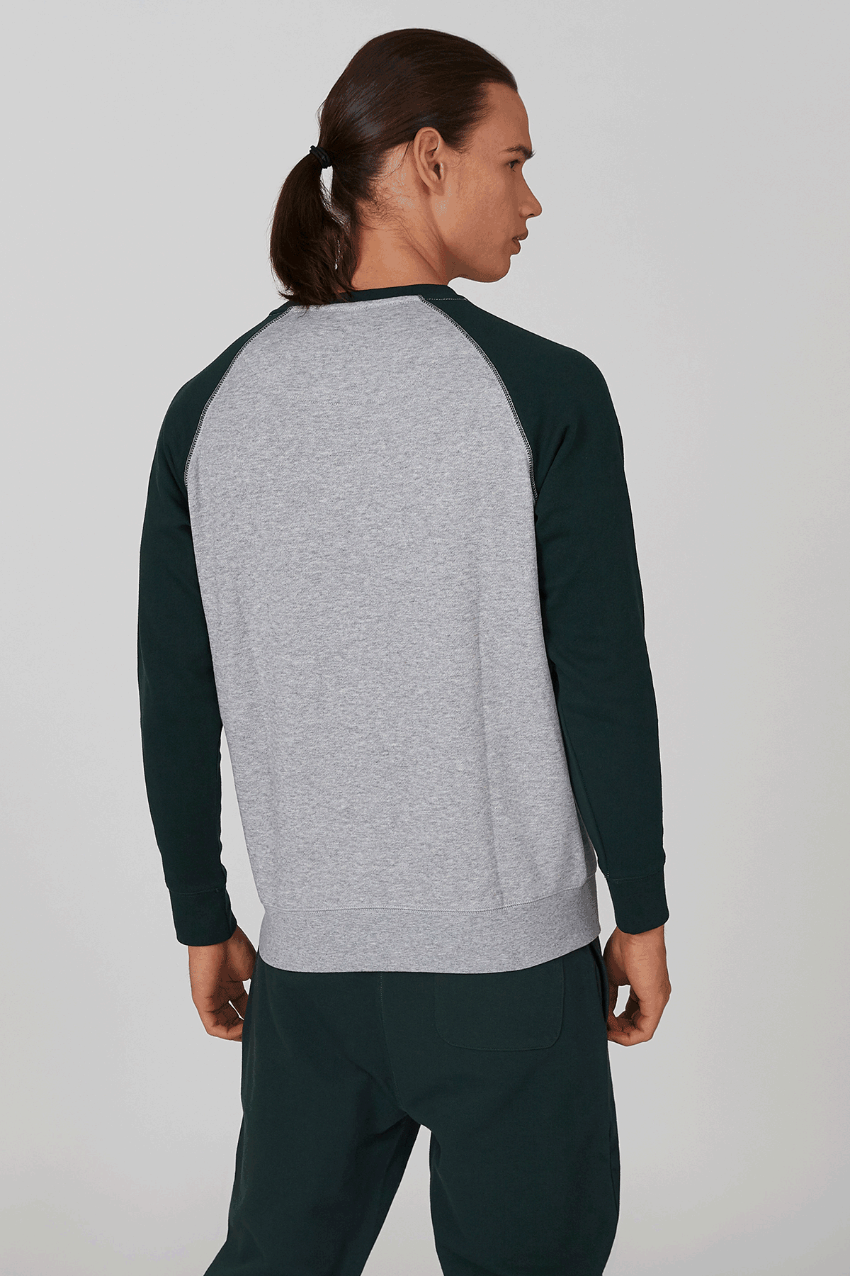 Back view raglan sweatshirt with heather-gray body and dark green sleeves, joggers visible