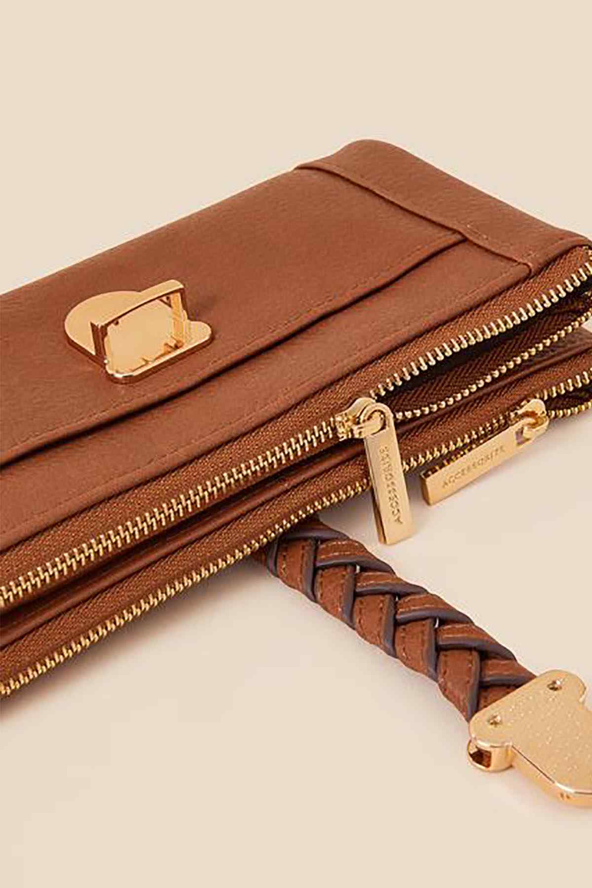 Tan leather zip pouch close-up with gold buckle clasp, dual zippers, and keyring pull