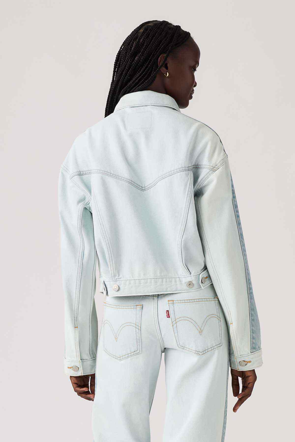 Light blue denim jacket back view with yoke stitching and buttoned cuff details