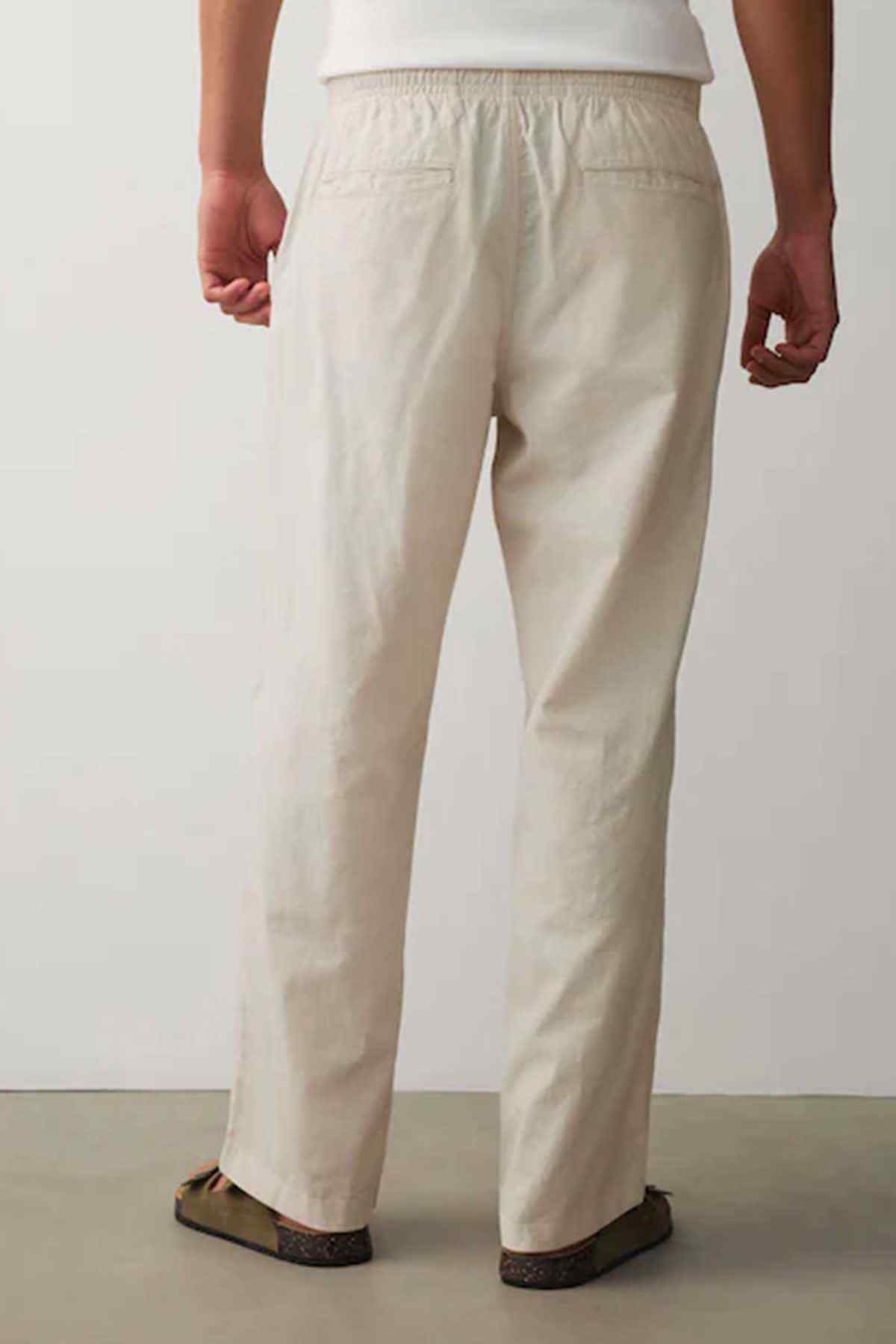 Cream drawstring waist trousers with tapered leg and front pleats