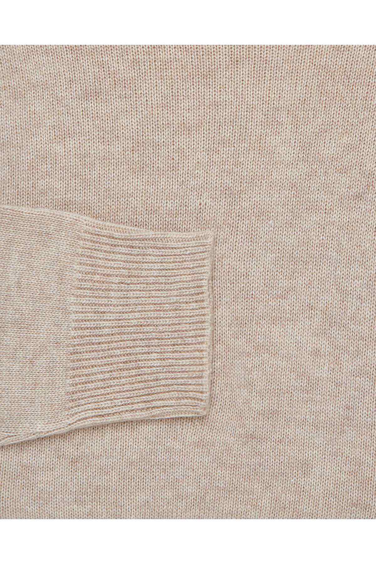 Cream knit sweater close-up of ribbed cuff and textured fabric