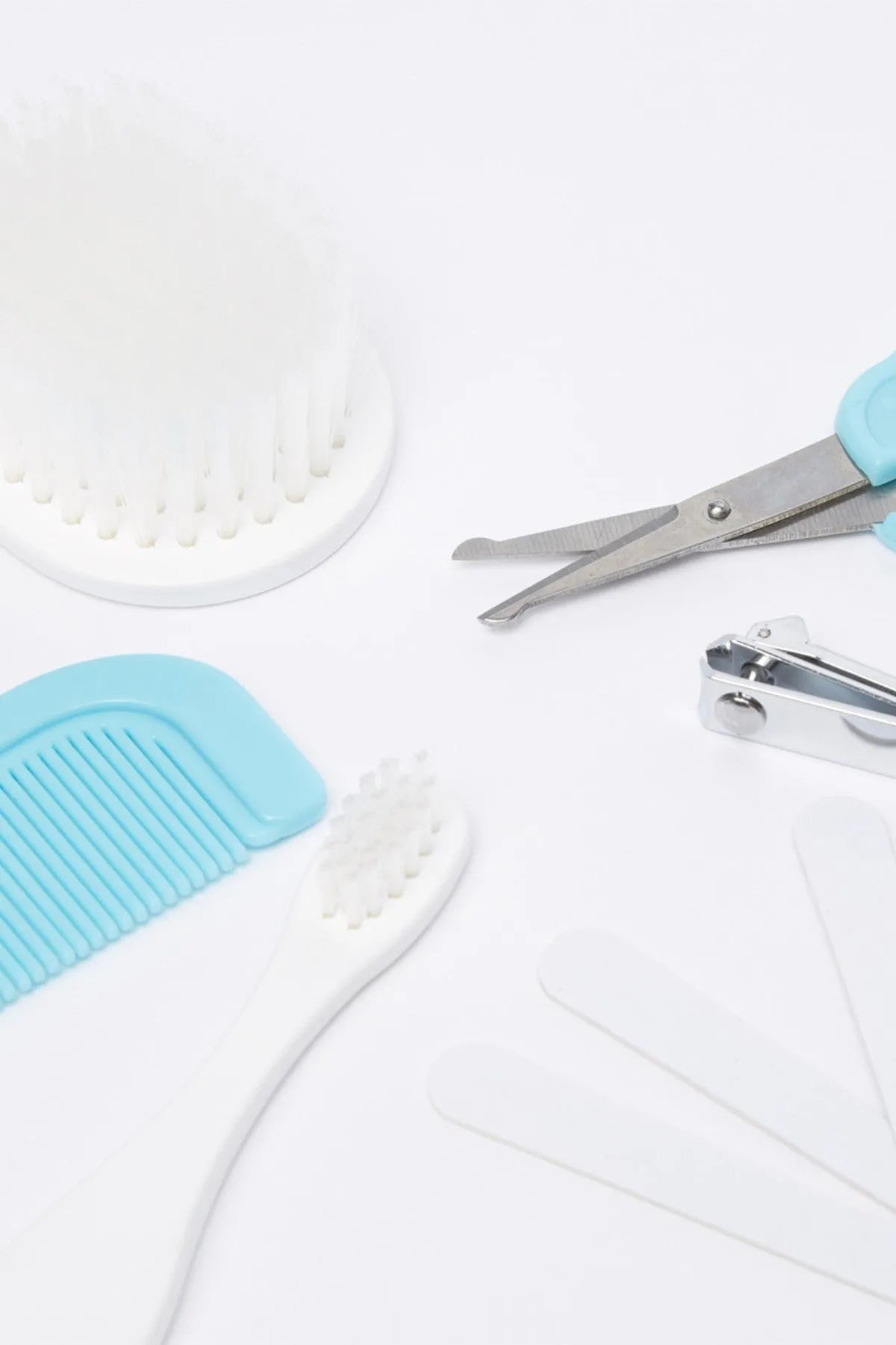 Baby grooming tool set close-up: blue comb, white brush, and metal scissors