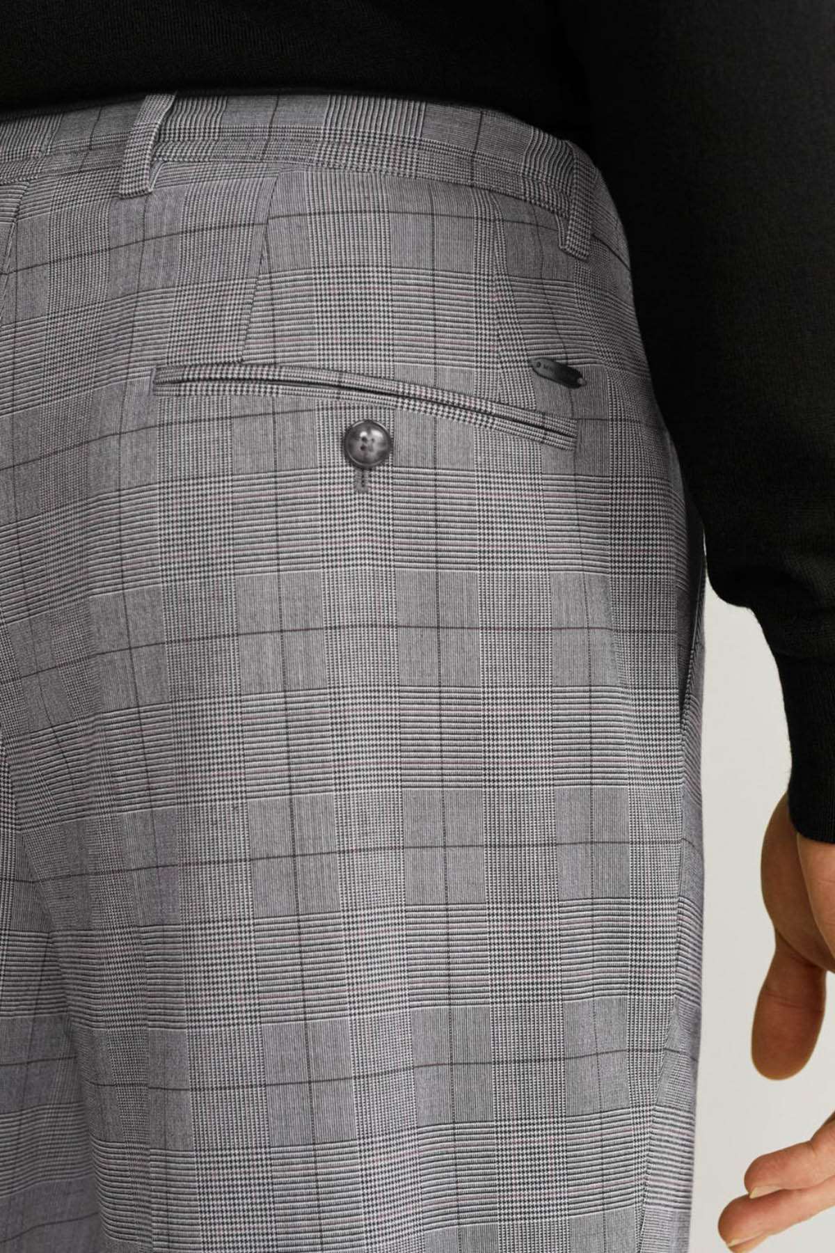 Men's light grey check trousers close-up of rear waistband and button tab