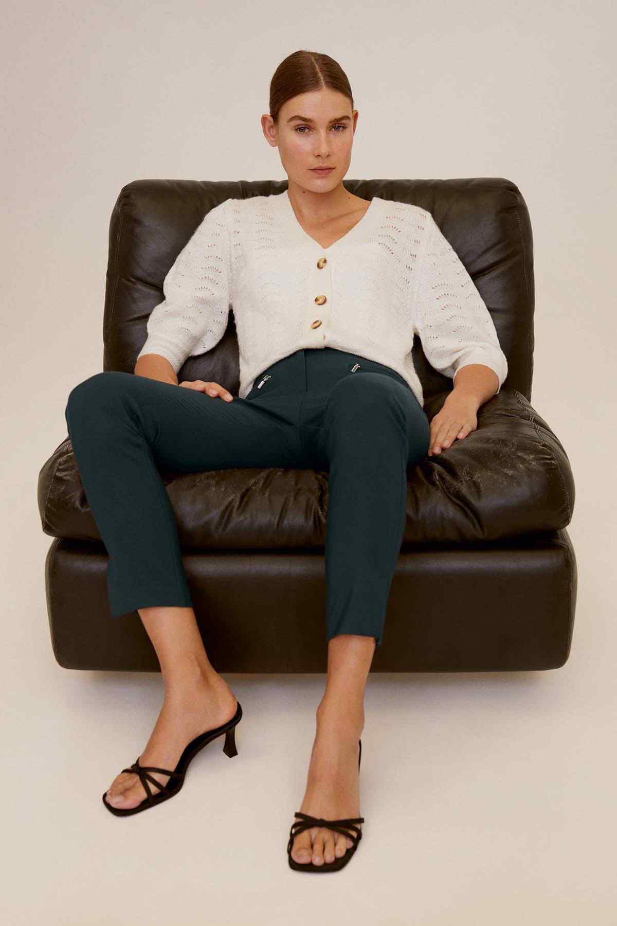 Dark green ankle-length slim pants with belt loops and back seam visible